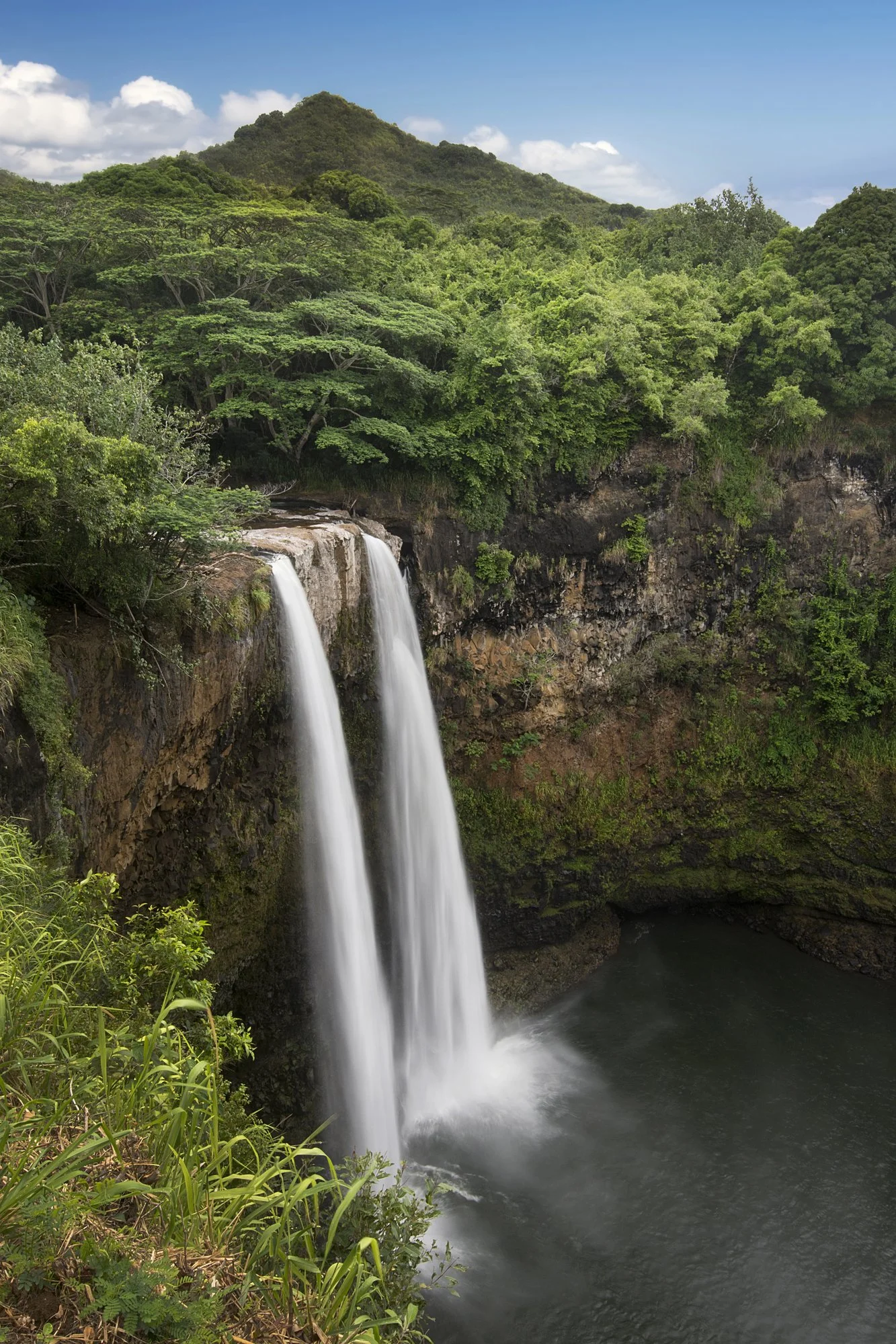 Lush tropical waterfall surrounded by rainforest in Hawaii, showcasing the natural beauty of the Hawaiian Islands.