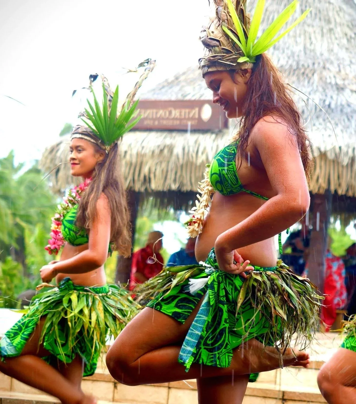 Local Polynesian dancers in traditional green leaf attire performing a cultural ceremony at a luxury resort, illustrating meaningful travel connections.