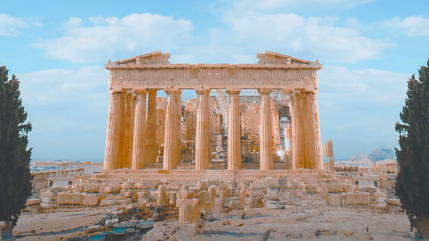 The Parthenon on the Acropolis in Athens beneath a blue sky with scattered clouds.