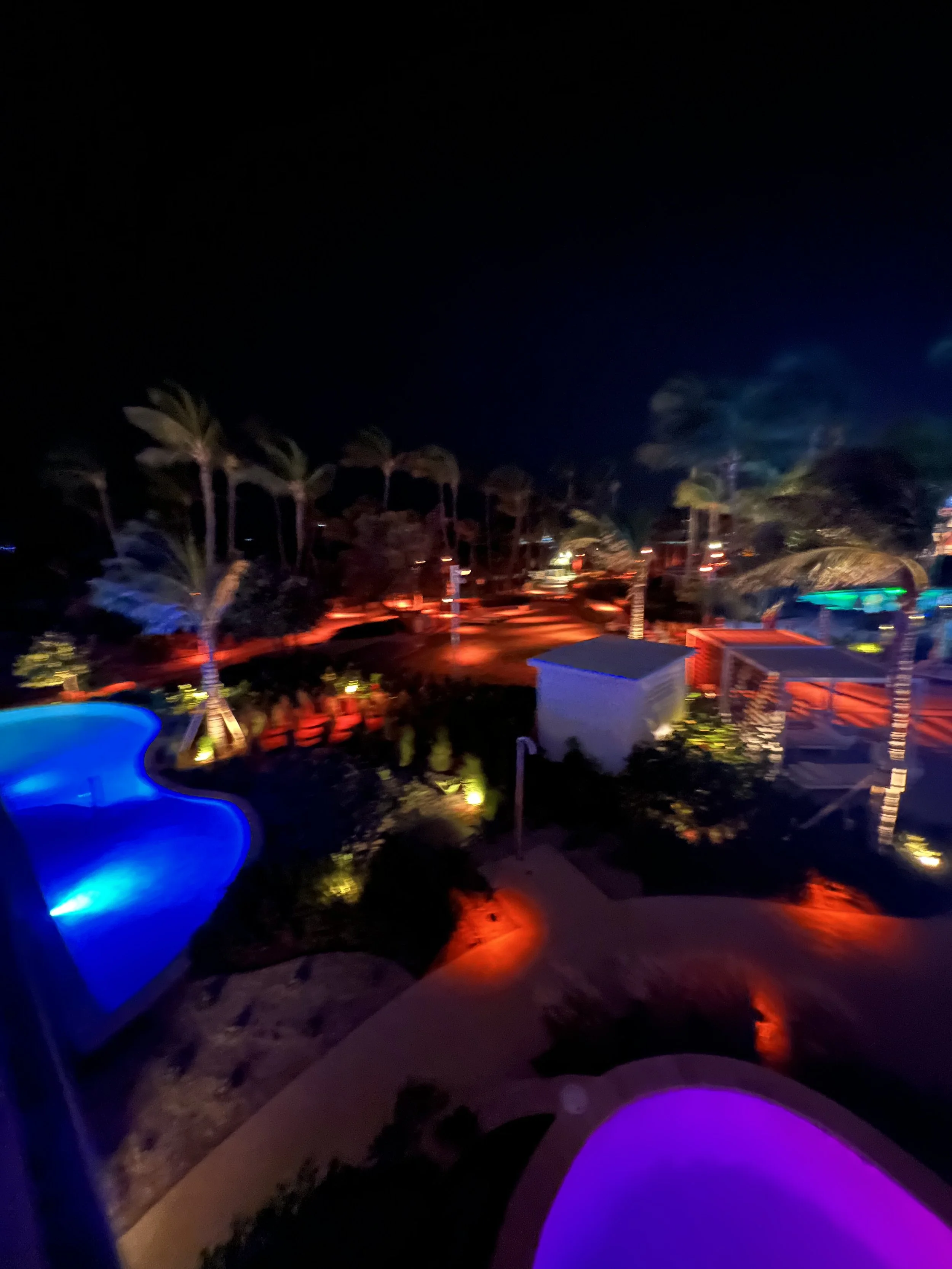 Resort pool glowing with colorful lights at night at Hilton Aruba