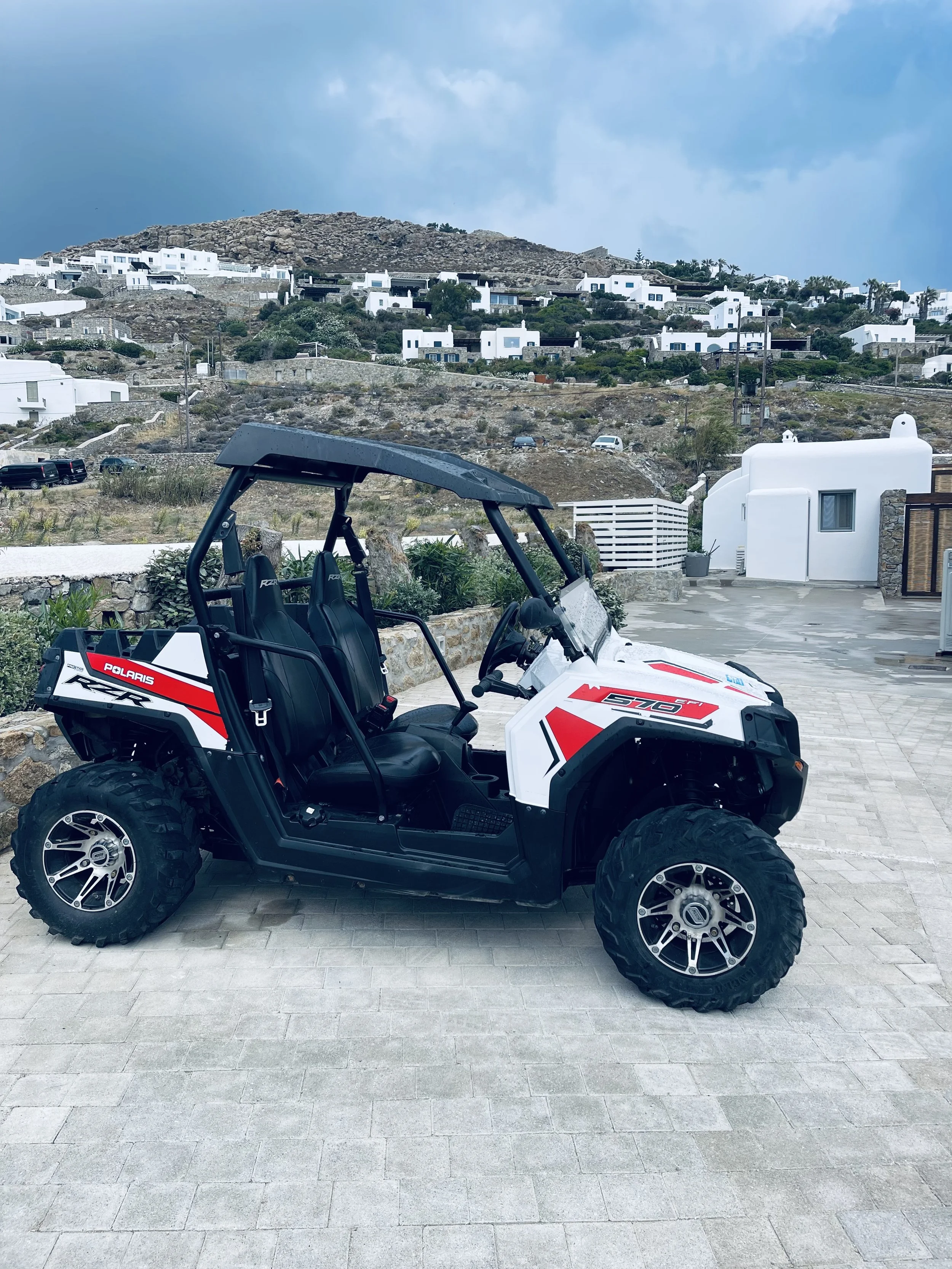 Four-wheel-drive buggy parked among white buildings on Mykonos, Greece