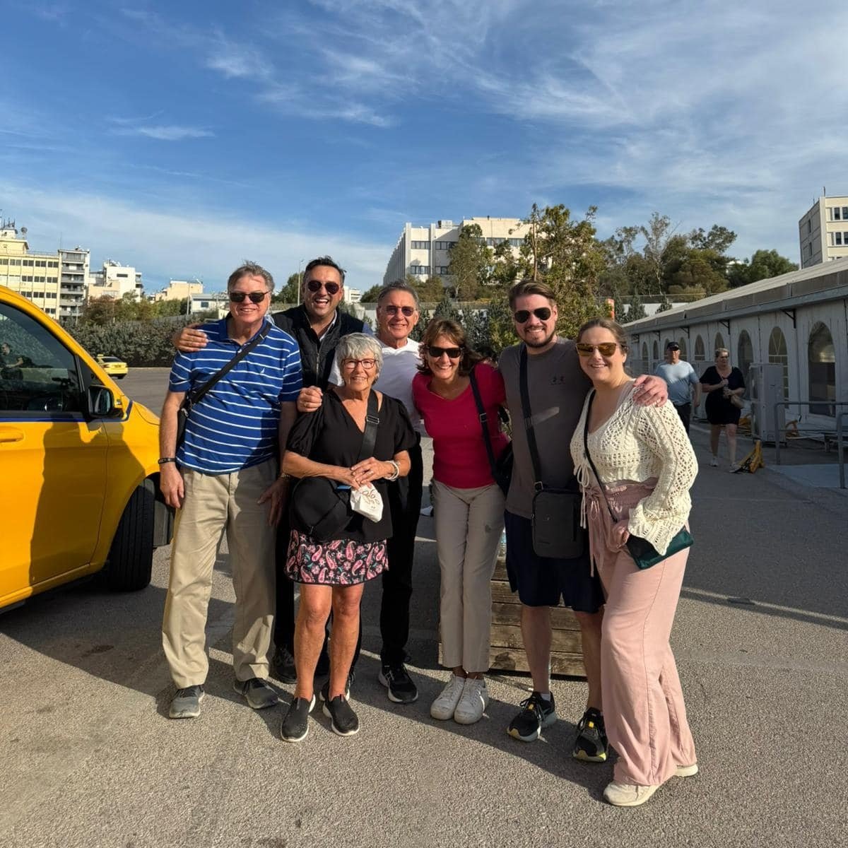 A diverse group of smiling travelers on a sunny day, showcasing expert coordination for multi-generational trips.