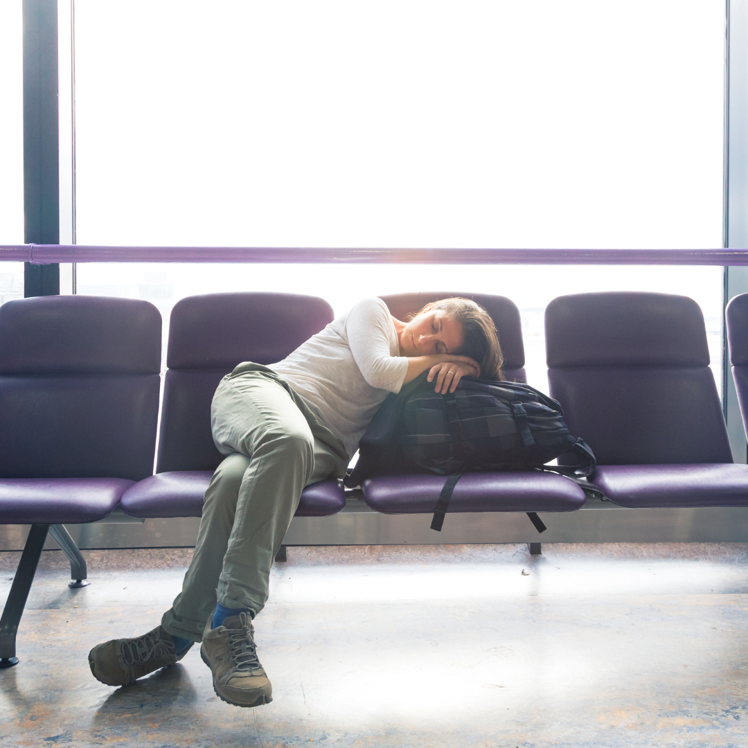 Capturing the reality of long-distance travel: a tired traveler naps on airport seating while waiting for a connecting flight.