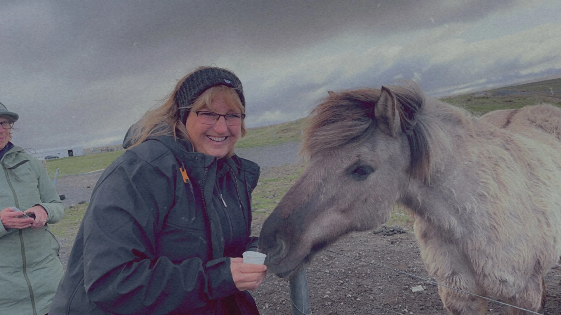 Jeanine smiling beside a horse during her Iceland vacation