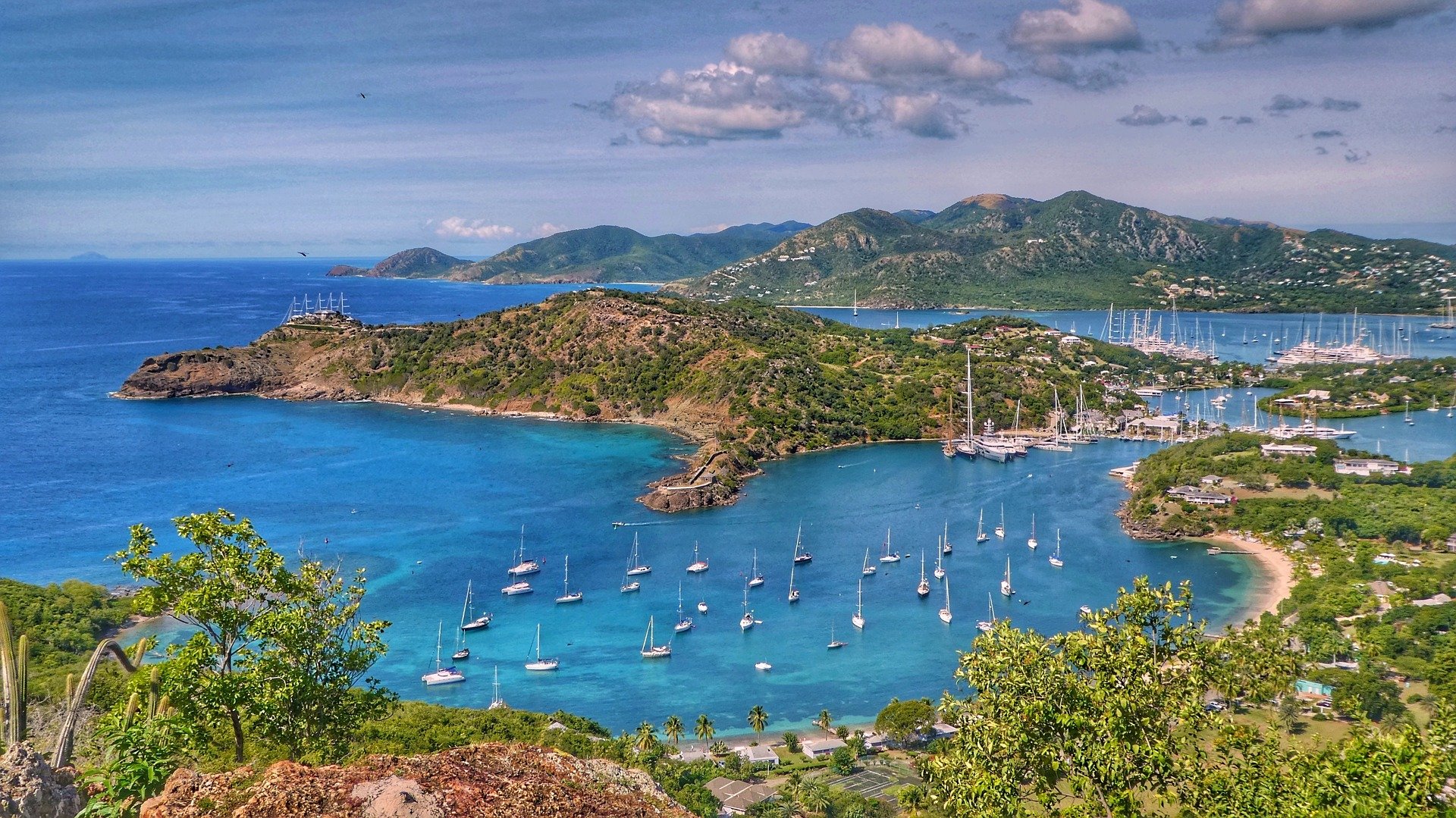 Small motorboat floating on crystal-clear turquoise Caribbean Sea near the coast of Antigua under a bright blue sky.