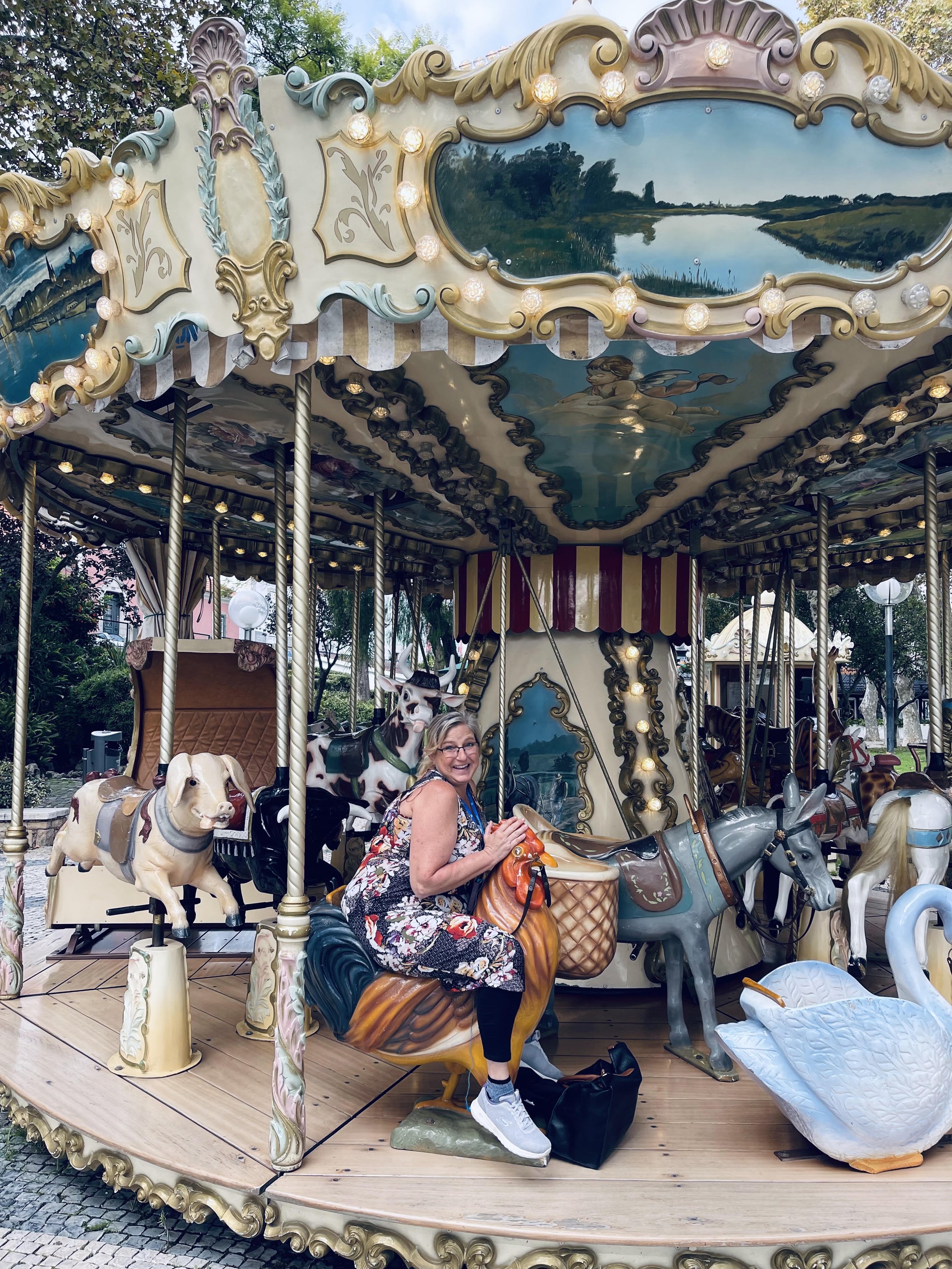 Jeanine Lavishly Travel riding a carousel in Cascais Portugal on an education trip. All Work and some play