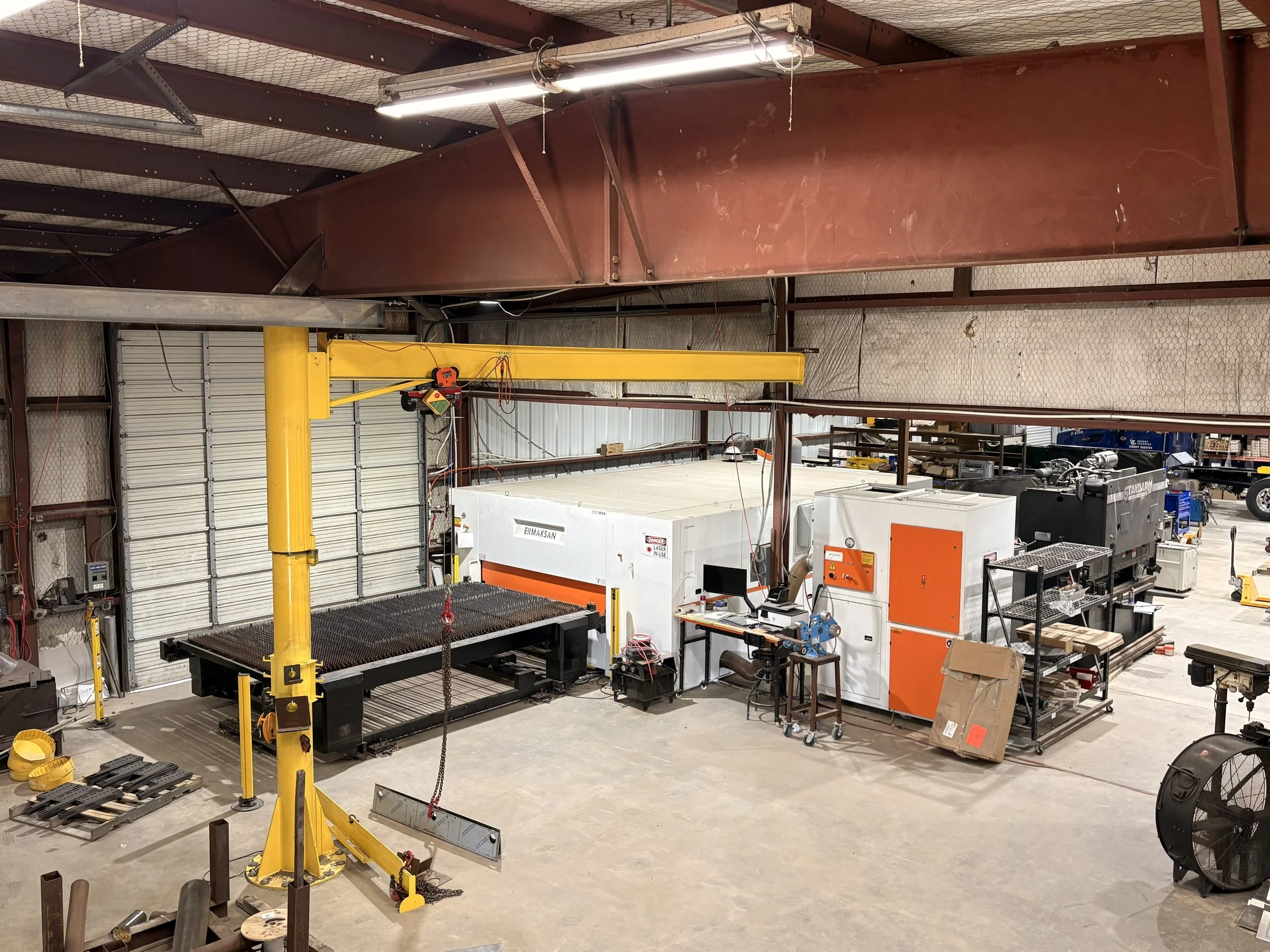 Industrial workshop with CNC plasma cutting machines, workbenches, tools, and equipment.