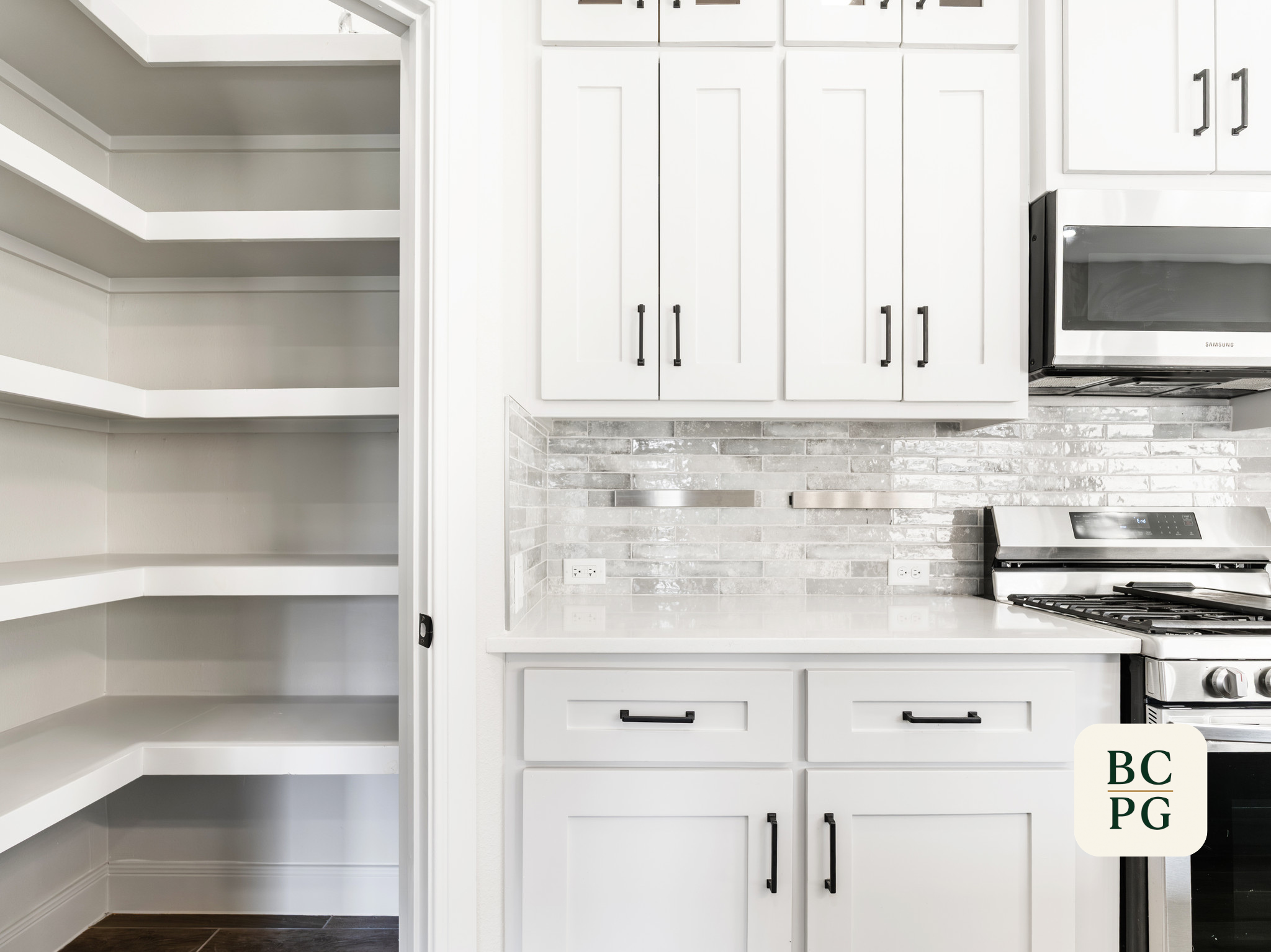 A modern kitchen with white cabinetry, a stainless steel microwave, a stove, a brick-style backsplash, and open shelving on the left side.