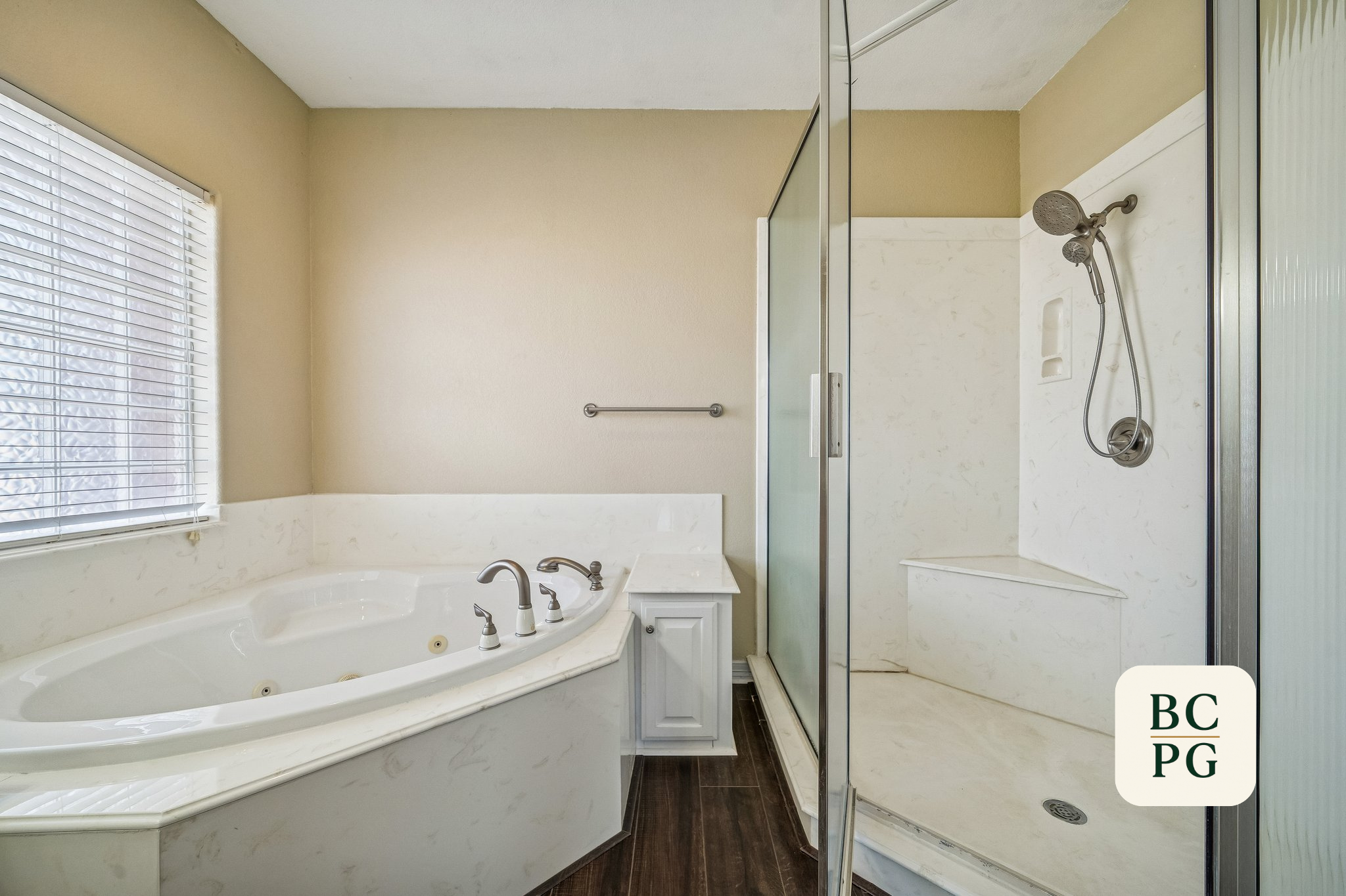 Bathroom with large window, bathtub, and walk-in shower with frosted glass door.
