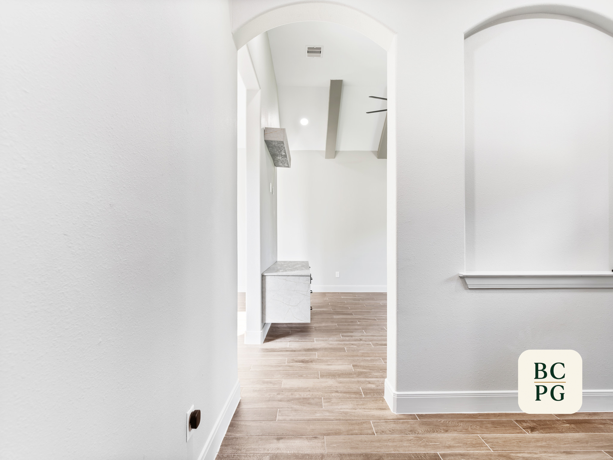 View of a hallway leading to an open doorway with a white interior, wood flooring, and a ceiling vent. The image is sent with a color overlay showing different license plate states.
