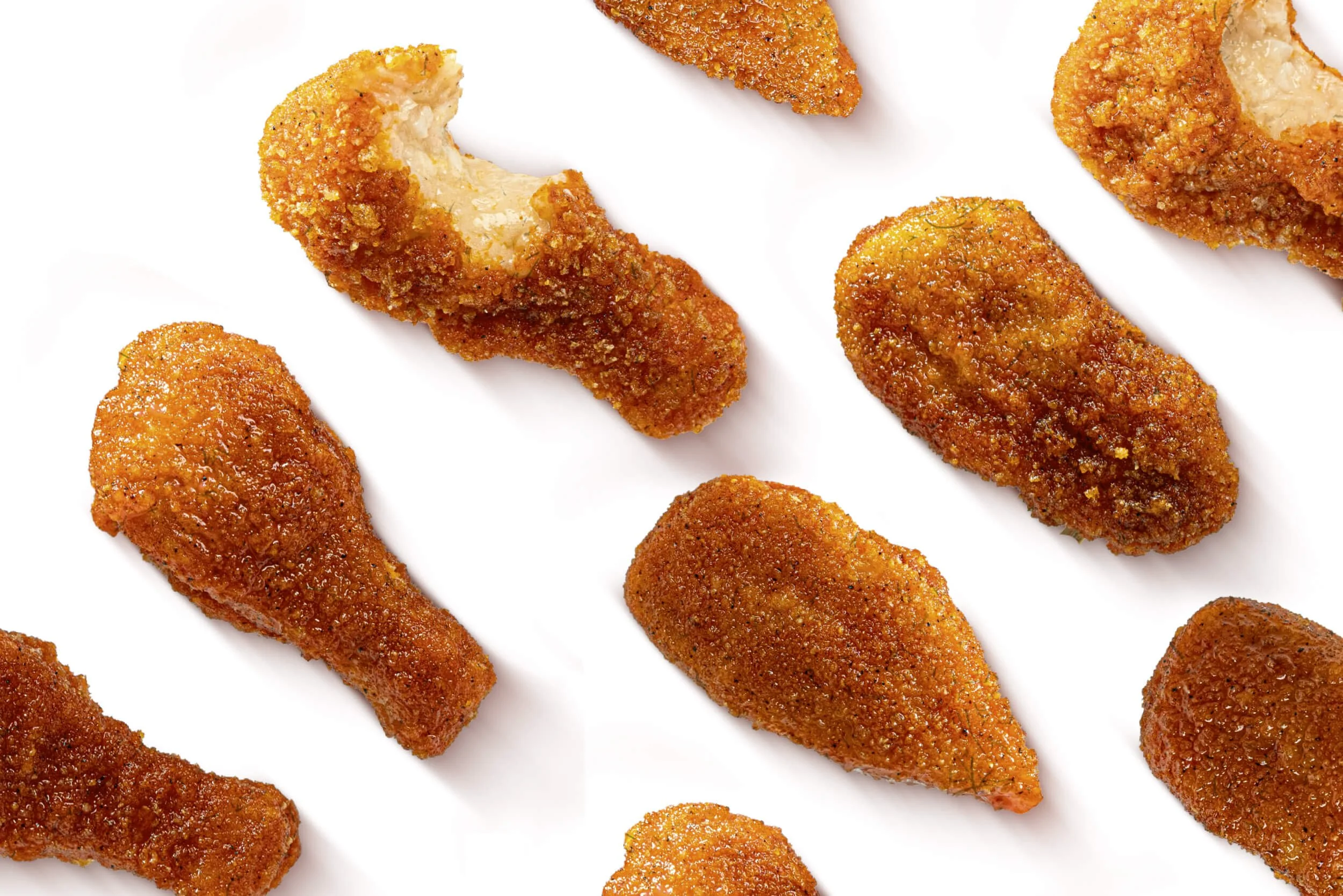 Several pieces of fried chicken drumsticks and breast pieces on a white background.