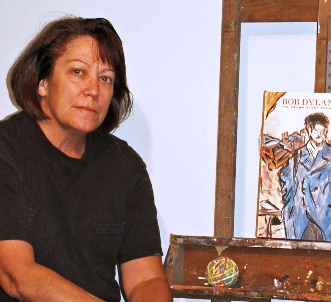 The artist next to her easel pictured with a book, The Drawn Blank Series, on one of her important influences 'Bob Dylan