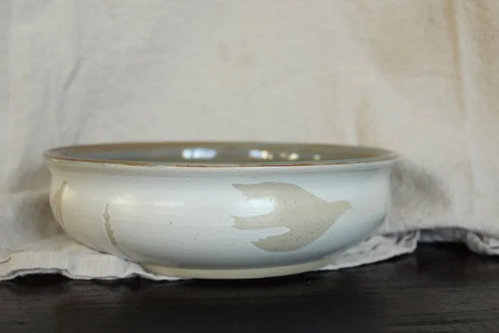 Claire Lemp Ceramics. Bozeman, MT Potter, pottery. Montana Ceramics, ceramicist. Made In Montana. A shallow ceramic bowl with a decorative pattern on the side, placed on a cloth surface.