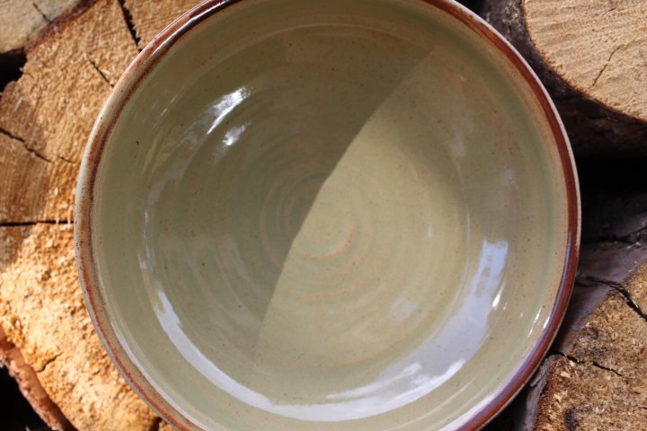 A ceramic bowl filled with clear water, placed on a wooden surface. Claire Lemp Ceramics. Bozeman, MT Potter, pottery. Montana Ceramics, ceramicist. Made In Montana.
