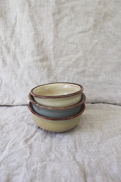 Stacked ceramic bowls on a fabric surface with a neutral background.