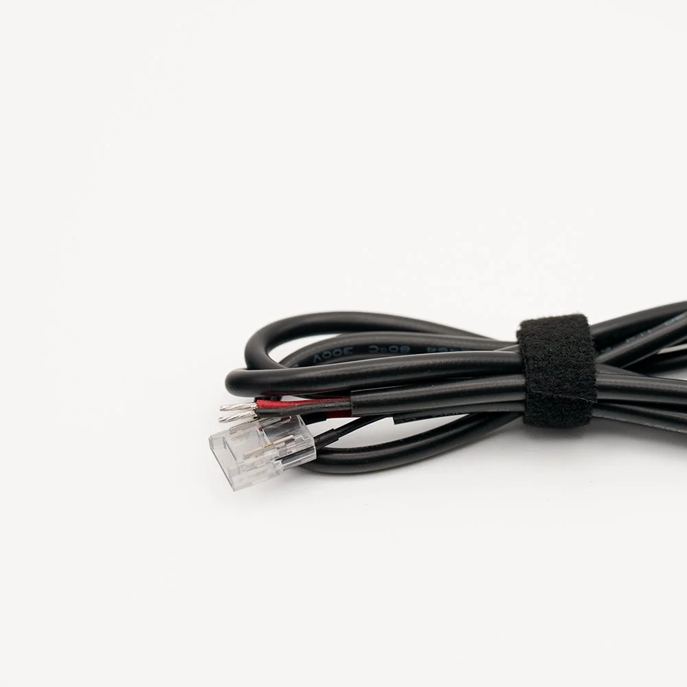 A bundle of black electrical wires secured with a Velcro strap, with one wire featuring a clear plastic connector.