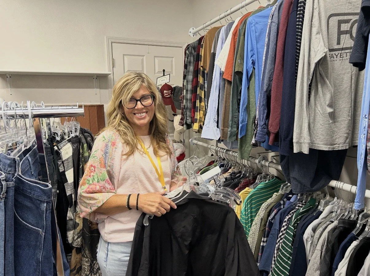 A volunteer sorts and hangs donated clothing on the racks at UpStart Thrift in Farmington, Arkansas