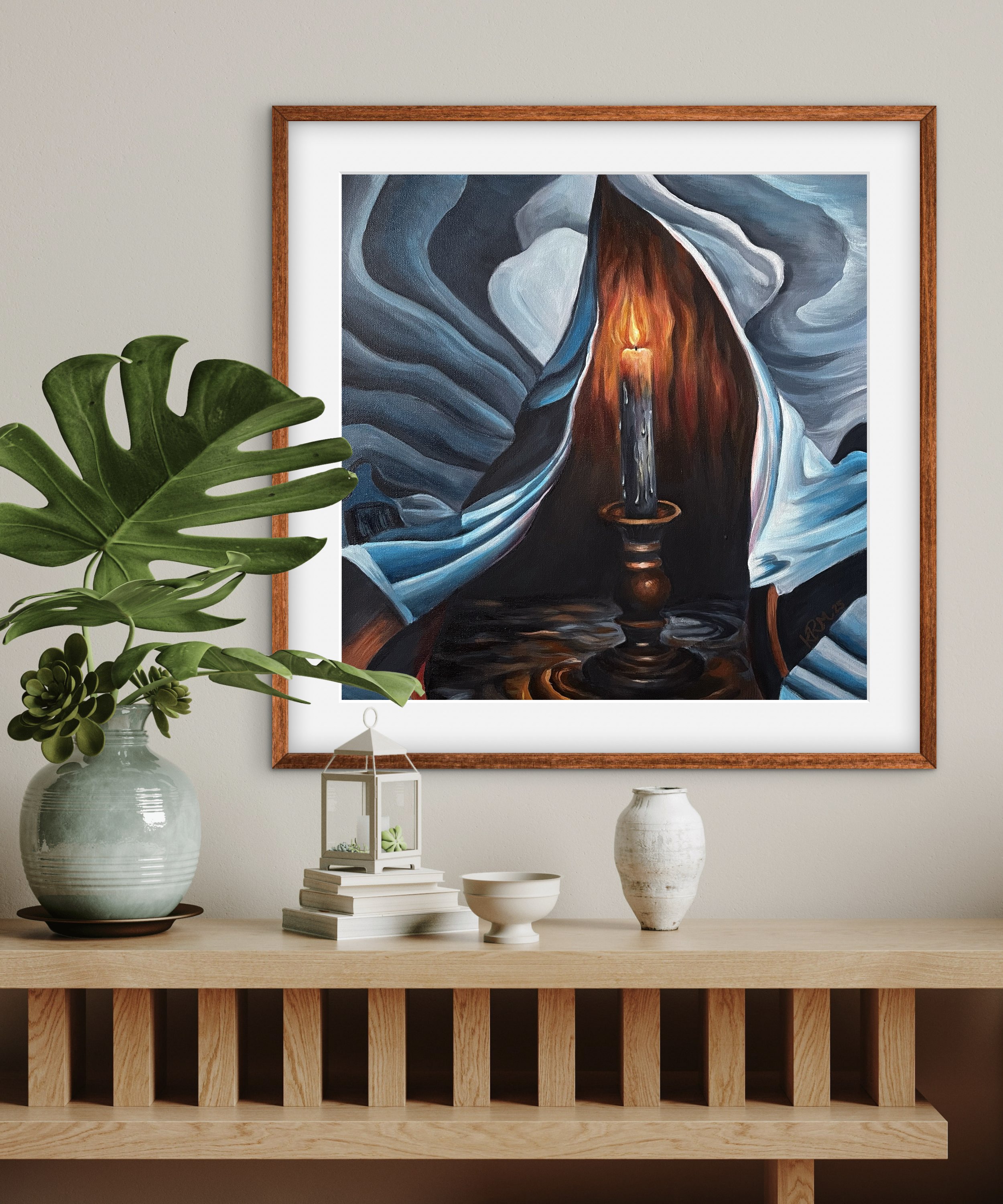 Painting of a candle with a fiery flame, surrounded by flowing blue and black abstract shapes, framed on a wall above a wooden table with decorative items.