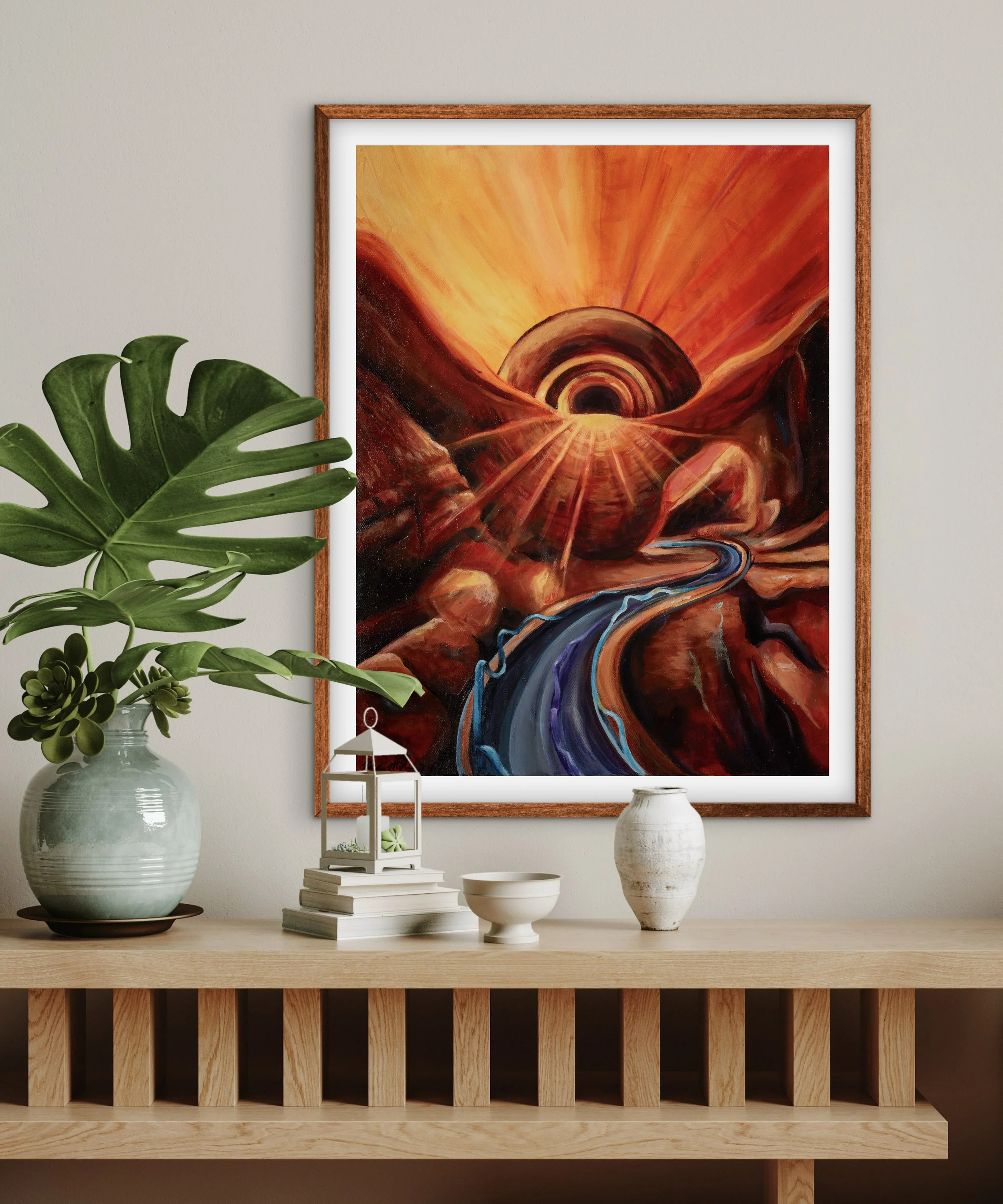 A colorful abstract painting with a sunset and river scene, hanging on a wall above a wooden sideboard with decorative plants and objects.