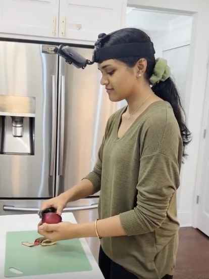 Photo shows a person at home wearing a headset while cutting an apple to show a first-person point of view for the Kintic dataset. Source: Kintic.