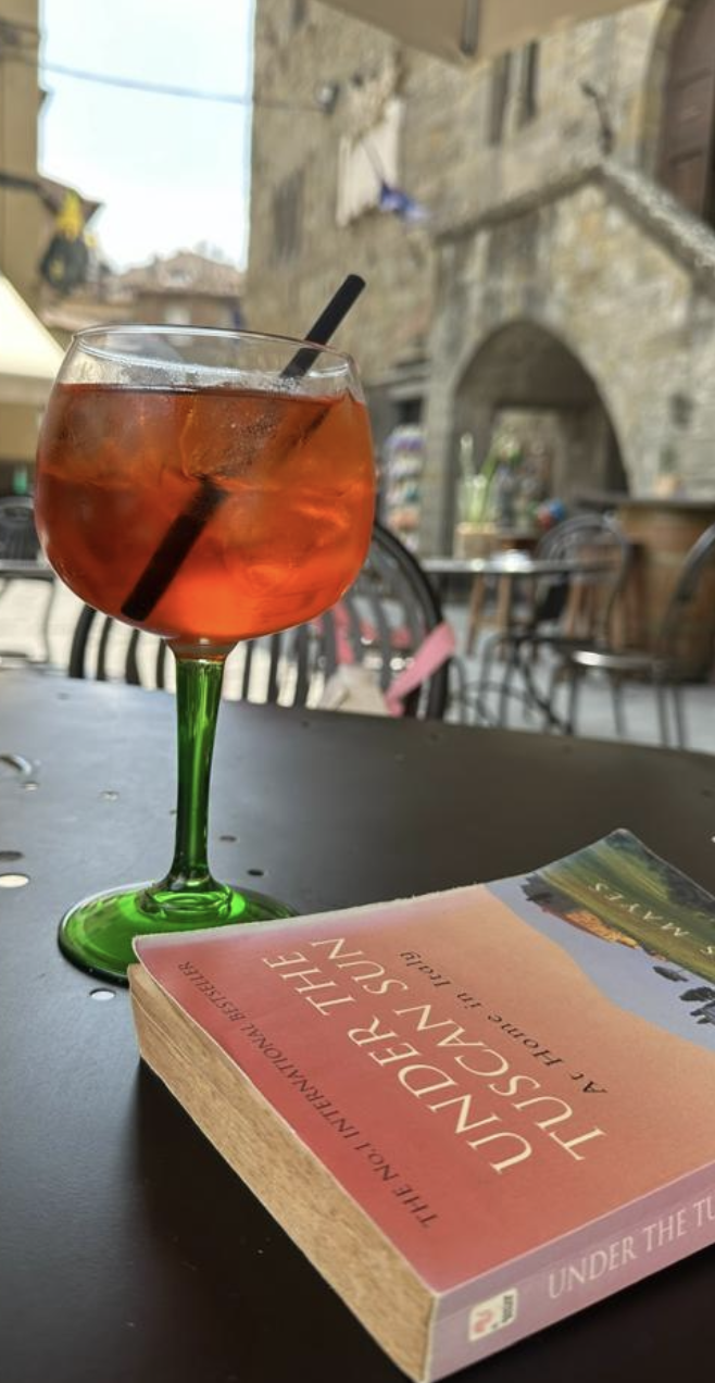 Aperold Spritz and under the tuscan sun on black table with old building in background in Cortona Italy