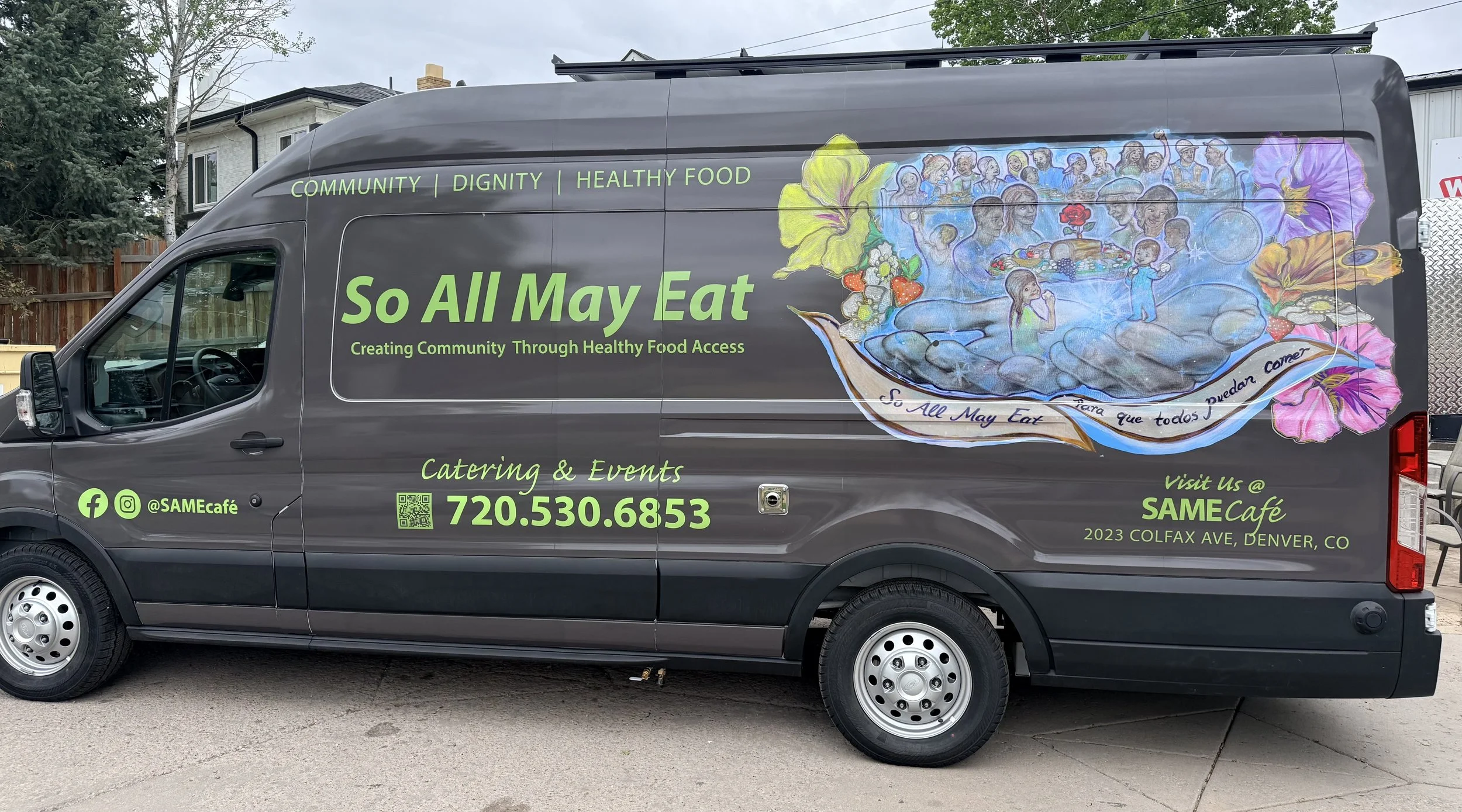 A catering van with vibrant artwork promoting community, dignity, health, and healthy food. The artwork features a large colorful bowl with people, flowers, and food items, along with text about creating community through healthy food access. The van