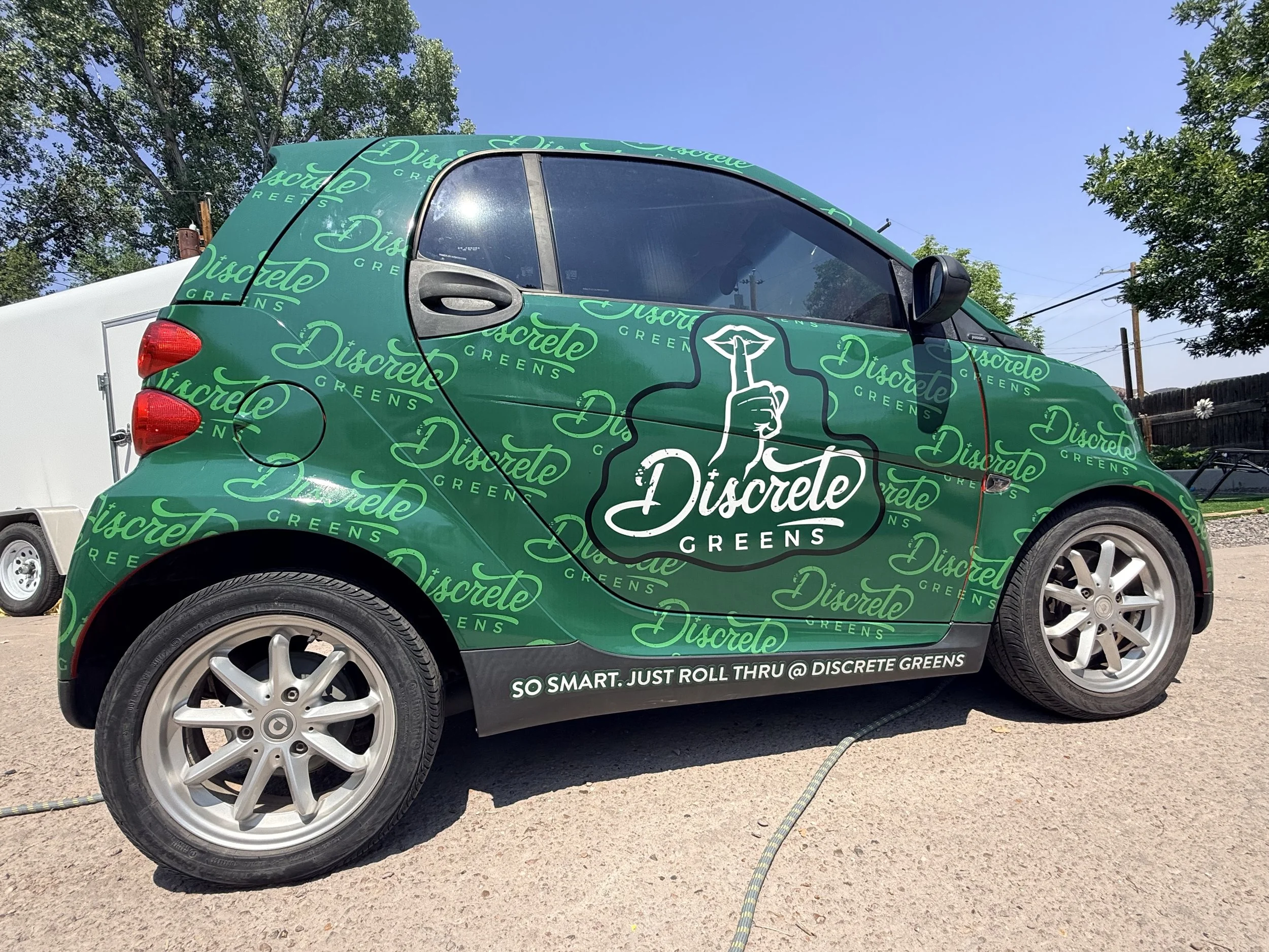 Green wrap on a Smart Car.  Branded pattern print with logo overlay.  Multiple green colors with clear branding.