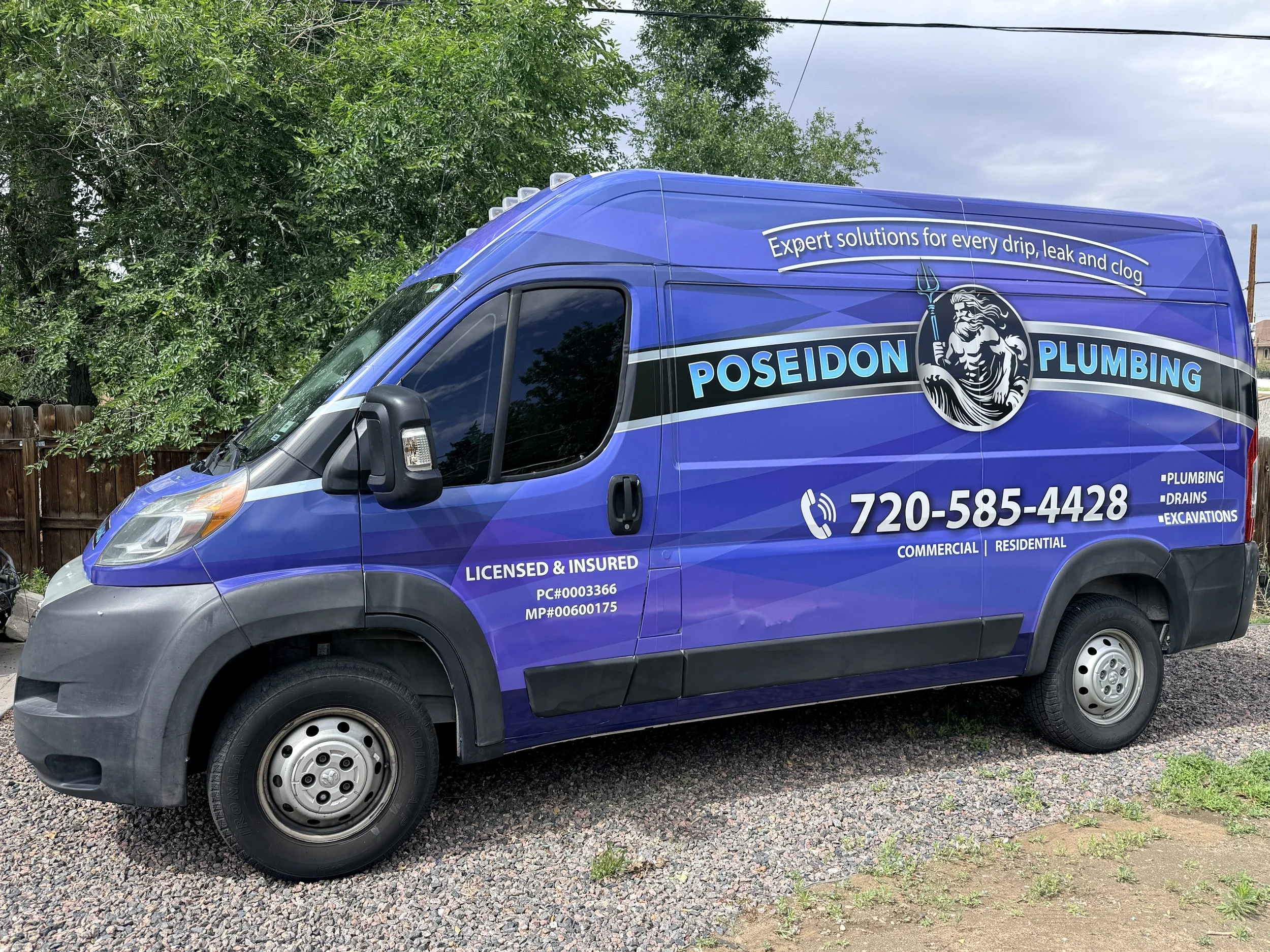 Blue Poseidon Plumbing service van parked on gravel with green trees and cloudy sky in background.