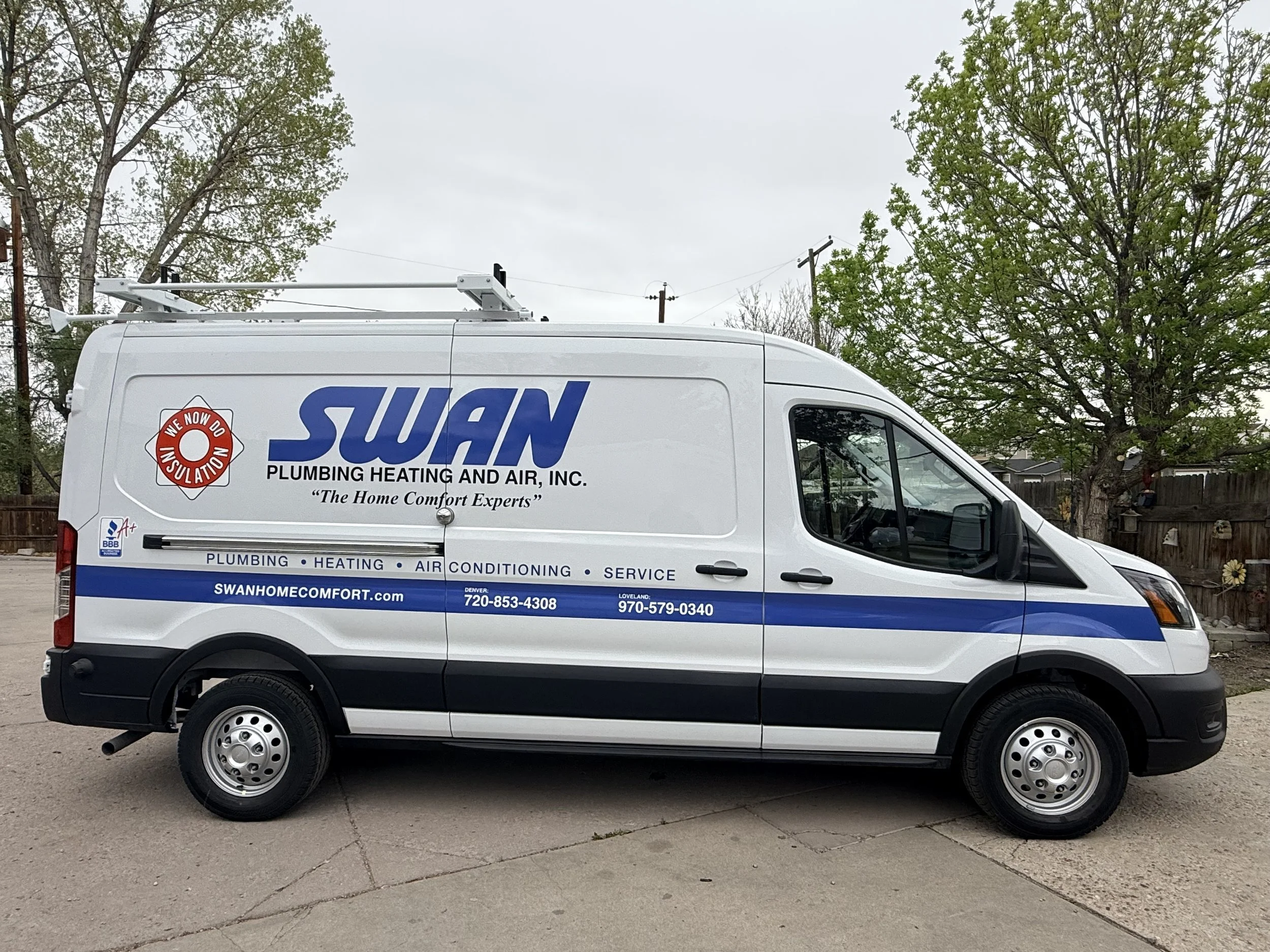 White service van with company name 'SWAN Plumbing Heating and Air, Inc.' parked on a driveway, with trees and power lines in the background.