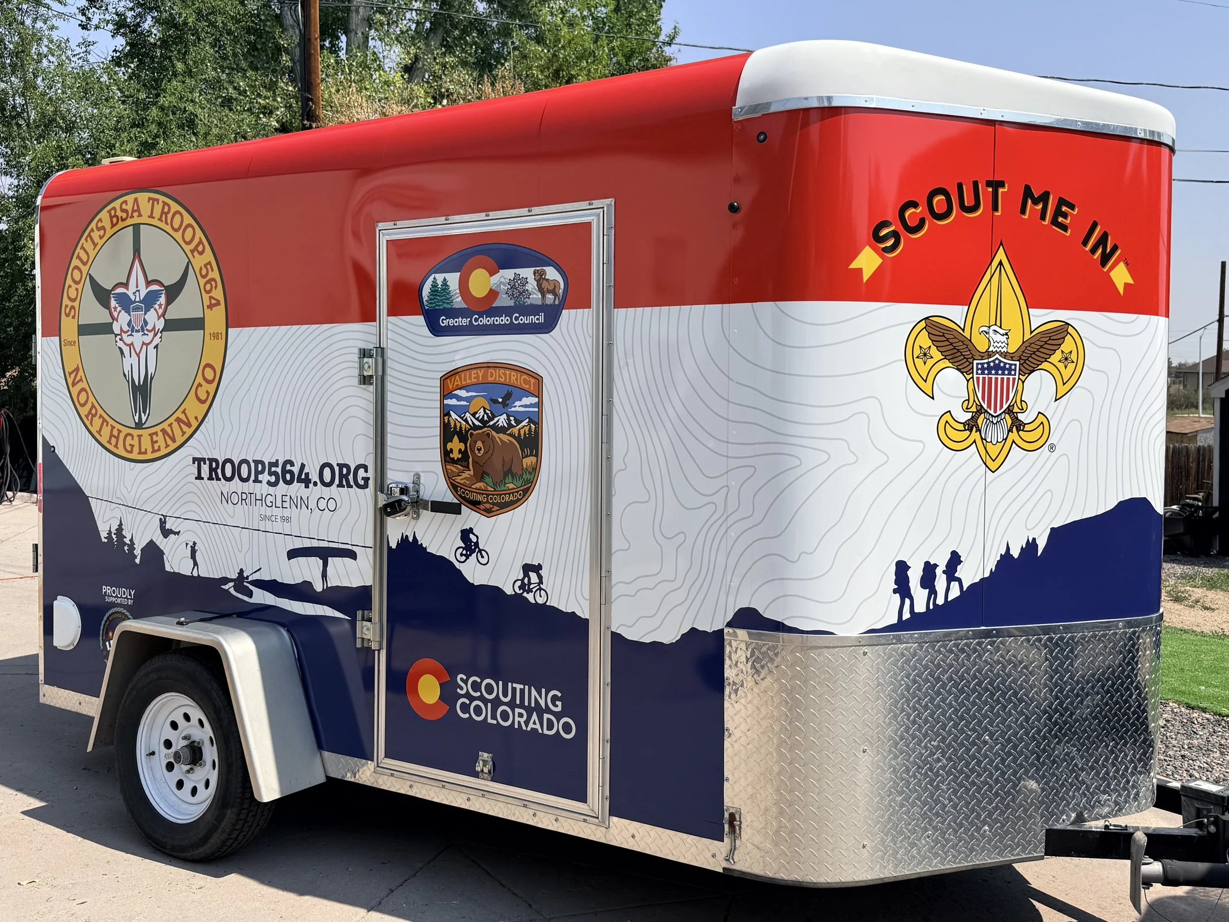 Multi-colored travel trailer for Scouts of America.  Topographical patterns, blue silhouette, and Troop 564 badging.