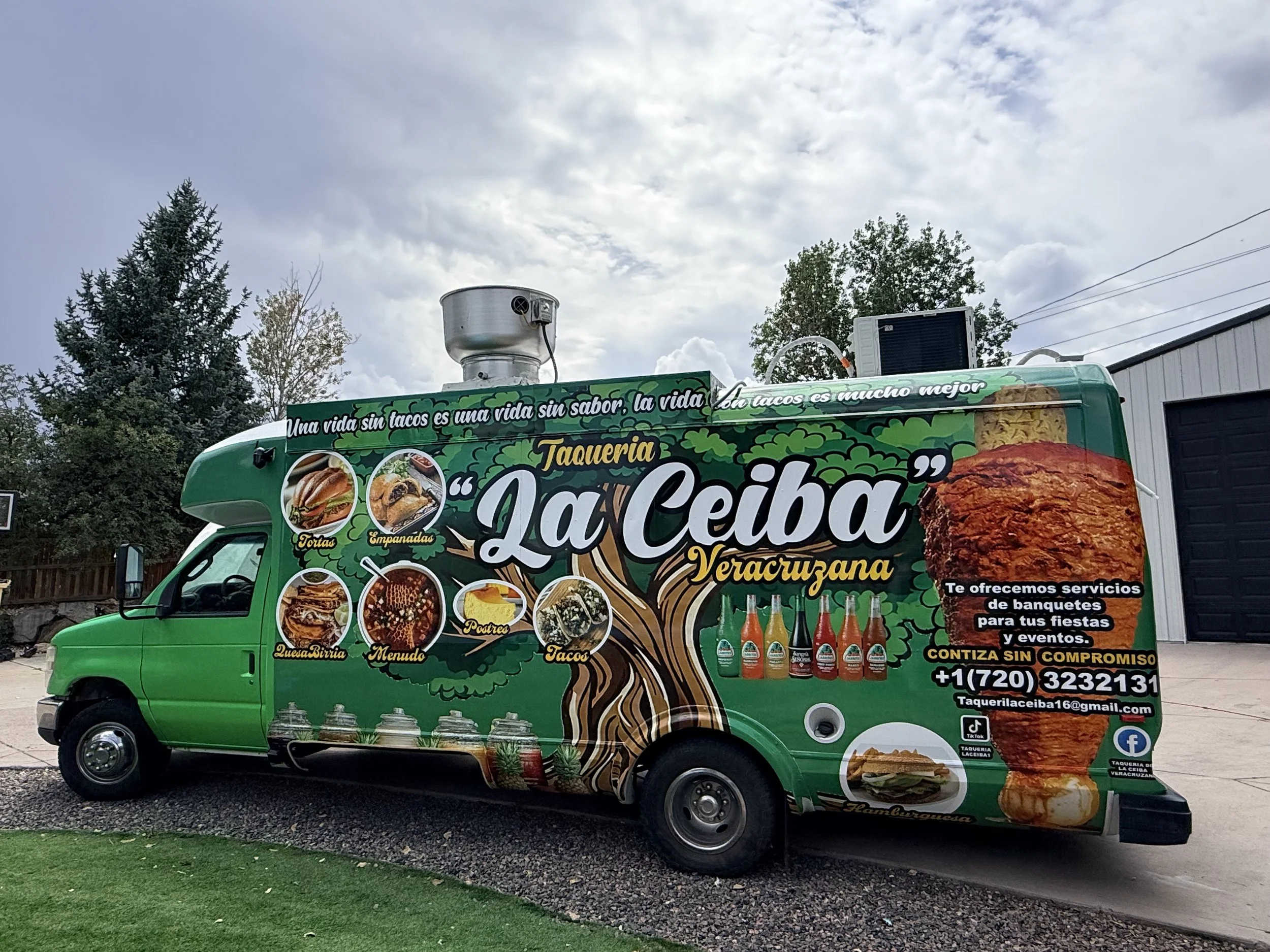 A vibrant green food truck with advertisements for tacos, tortas, empanadas, barbecue, postres, menus, and tacos. The truck features images of various dishes, a large roasted meat, bottles of beverages, and contact information, including phone number