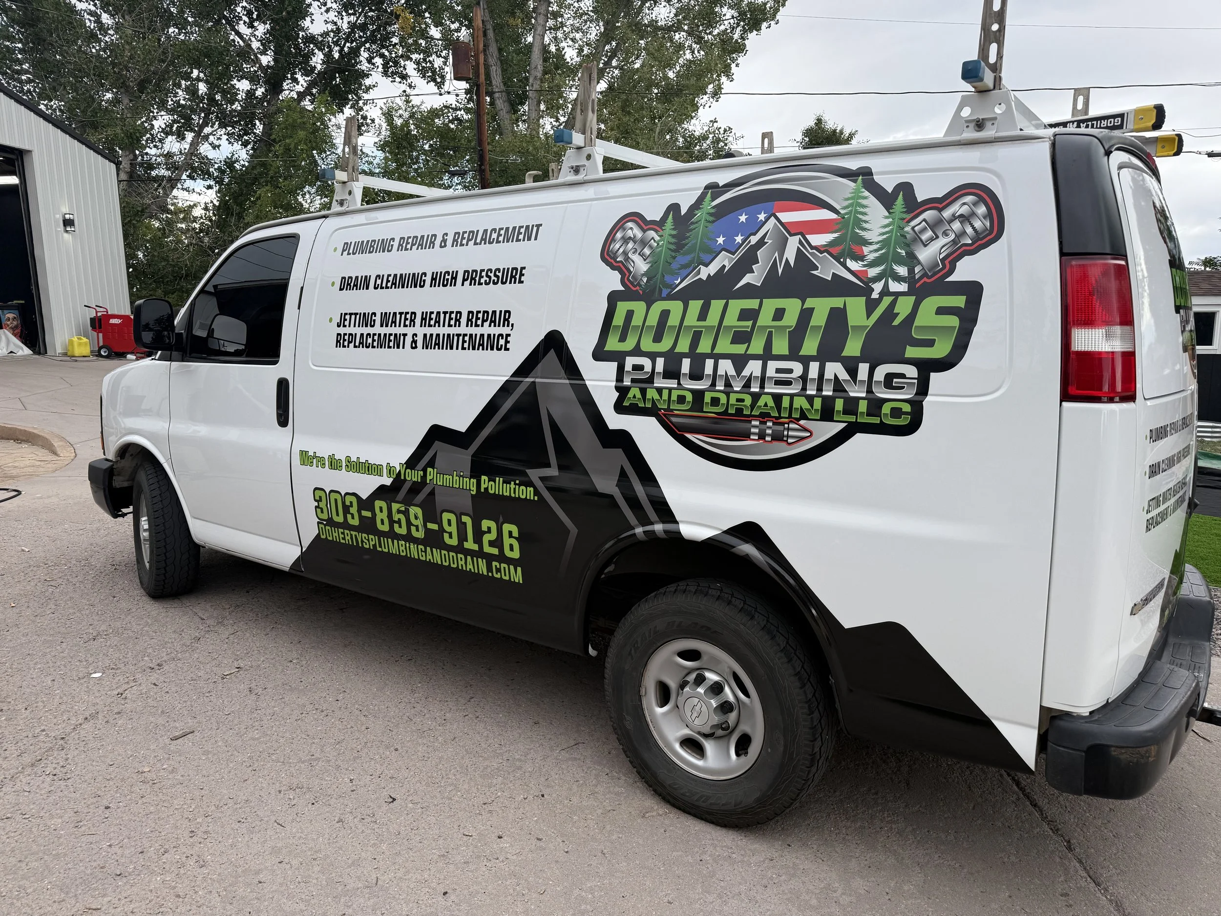 A white service van with branding and contact information for Doherty's Plumbing and Drain LLC, parked outdoors near a building and trees. The van lists plumbing services such as repair, drain cleaning, and water heater repair.