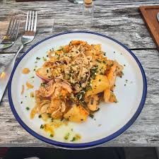 A plate of food with roasted vegetables, cheese, and herbs on a rustic wooden table.