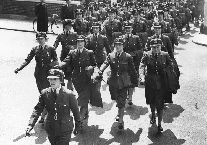 A group of women in military uniforms marching in formation during daytime