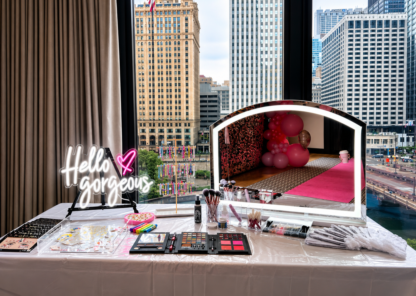 Glam Bar makeup and glitter station by Blush & Bliss by Mya overlooking downtown Chicago, featuring an LED mirror, cosmetics, face gems, glitter, and a “Hello Gorgeous” sign for birthdays, Bat Mitzvahs, Sweet 16s, and private events.