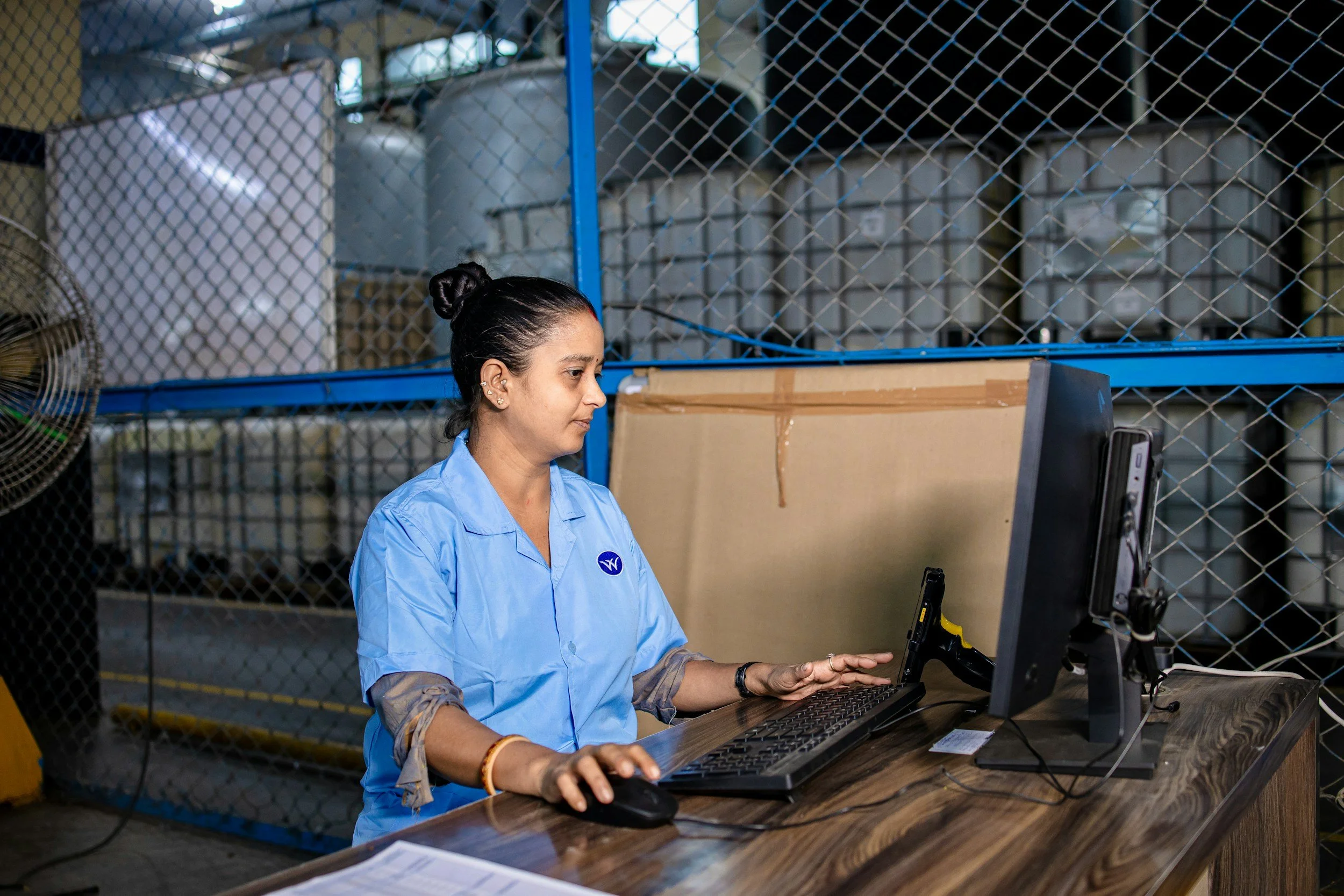 Manufacturing employee working at a computer near the production floor