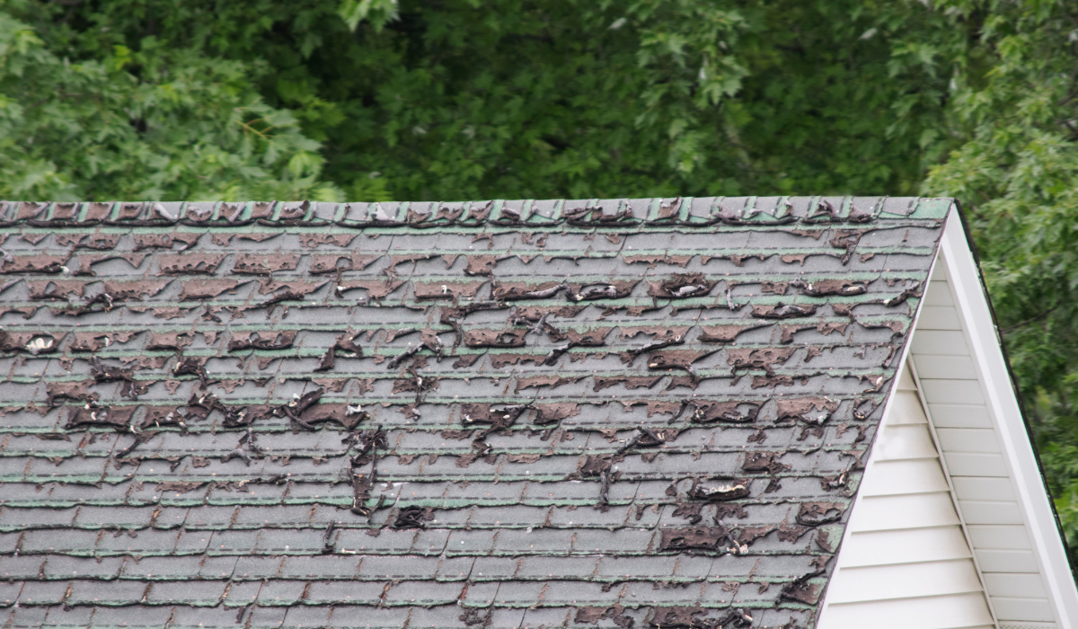 Worn roof shingles and deteriorated flashing showing age-related roof damage
