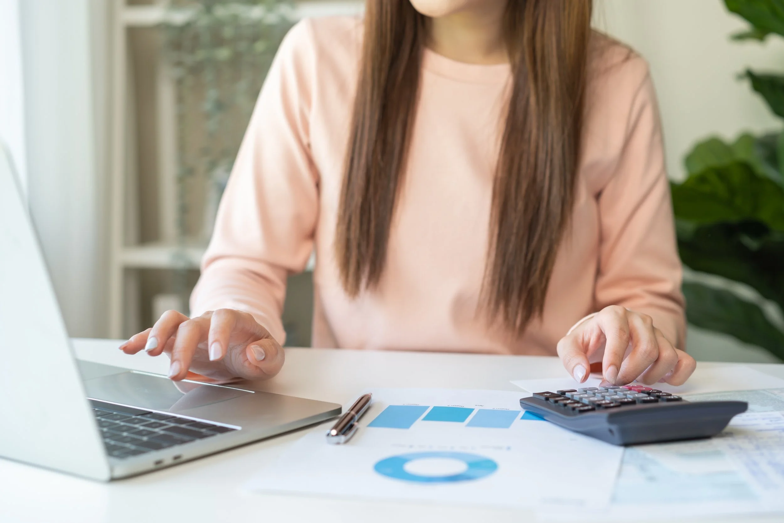 Person calculating yearly expenses while comparing annual insurance payment costs.