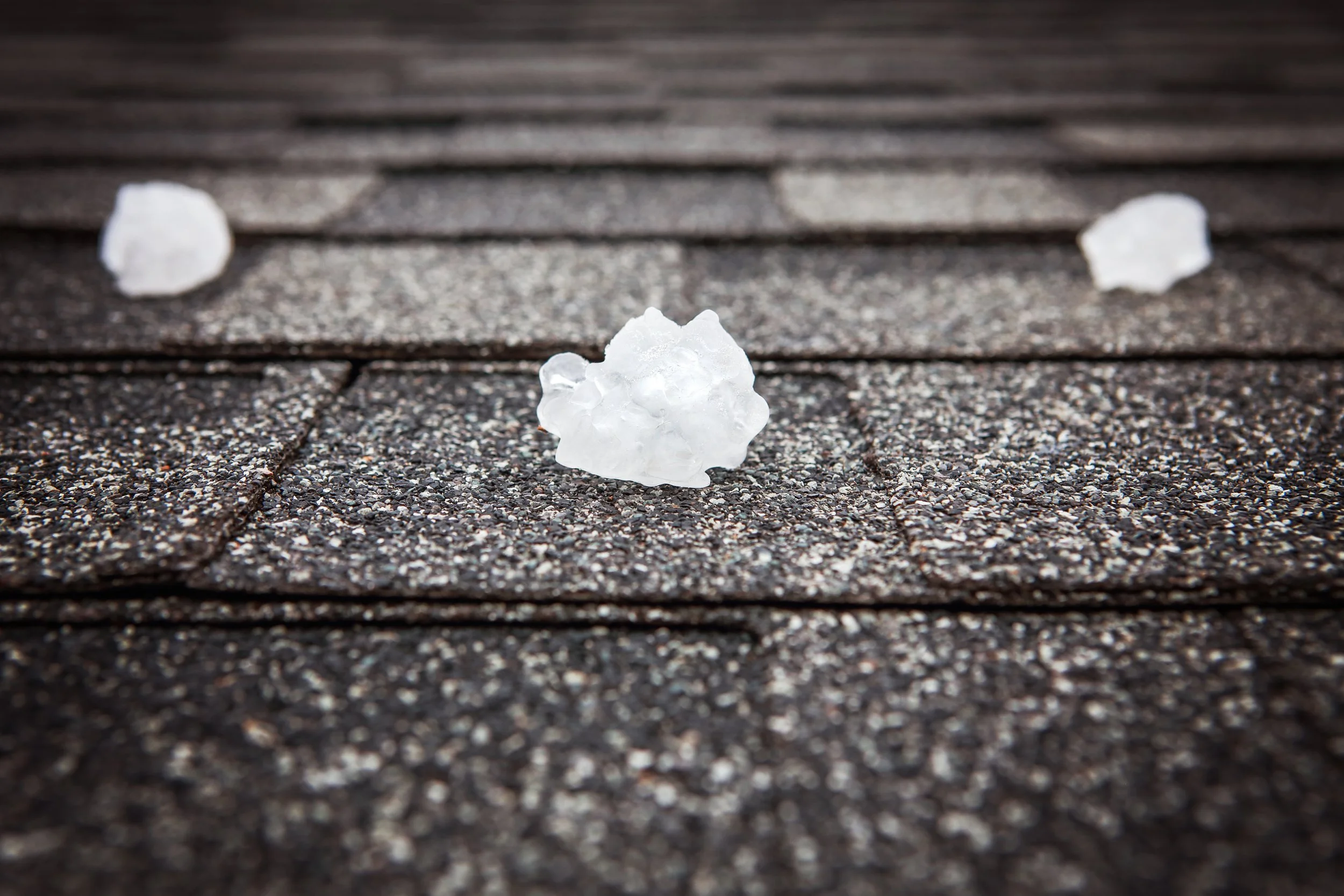 Hail stones resting on an asphalt shingle roof after a severe storm.