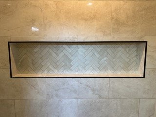 A rectangular, horizontally oriented mirror with a black frame, embedded in a beige tiled floor.