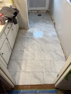 Renovated bathroom floor with white subway tiles, partially finished with some tools and construction debris visible.