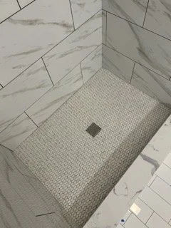 Shower floor with small mosaic tiles and a central drain.