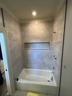 Bathroom shower area with light-colored tiled walls and a built-in niche for toiletries.