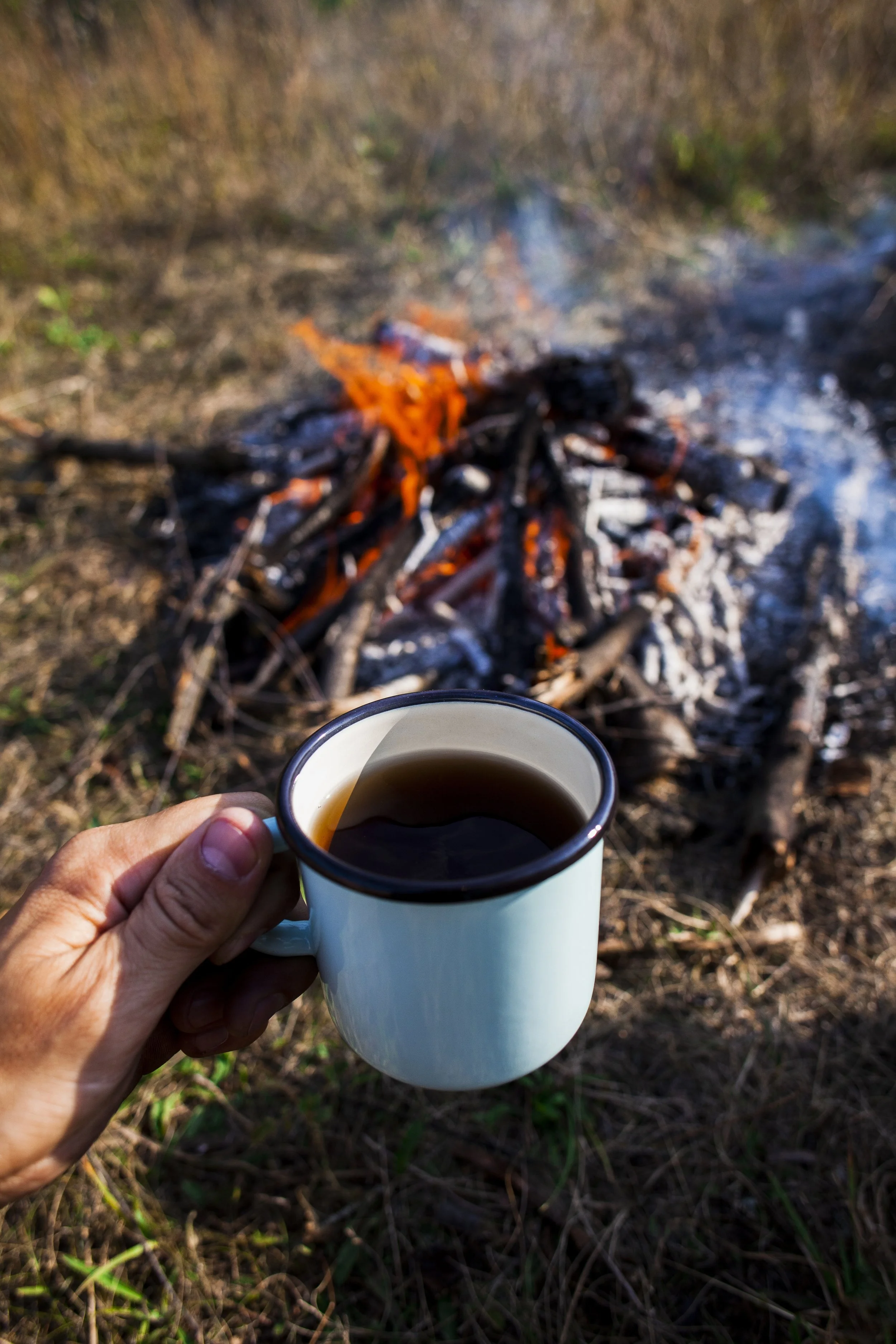 hand-holding-cup-coffee-campfire.jpg