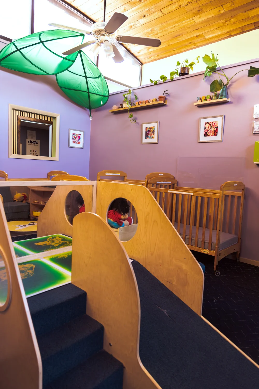 Our infant room with cribs, a soft climber, and a sensory floor