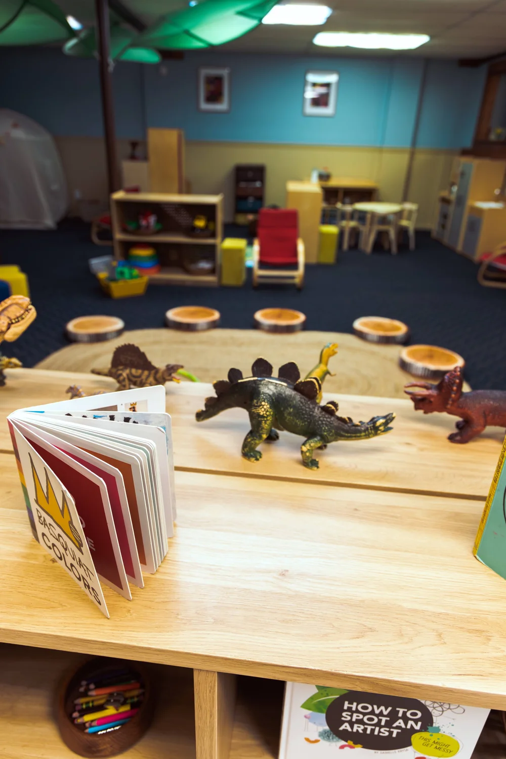 Books and toy dinosaurs on a wooden table in the preschool room