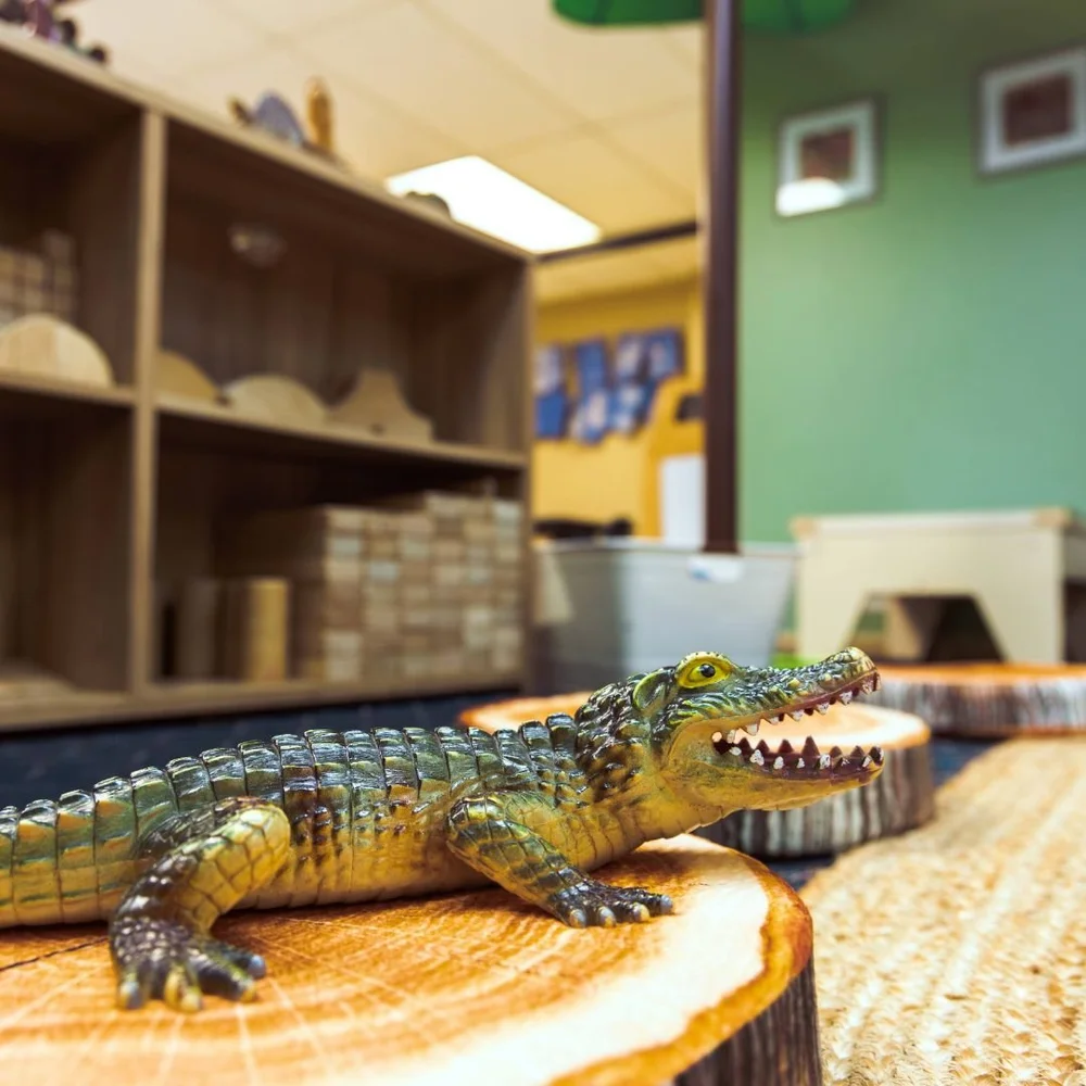 A toy alligator on a tree-stump seat
