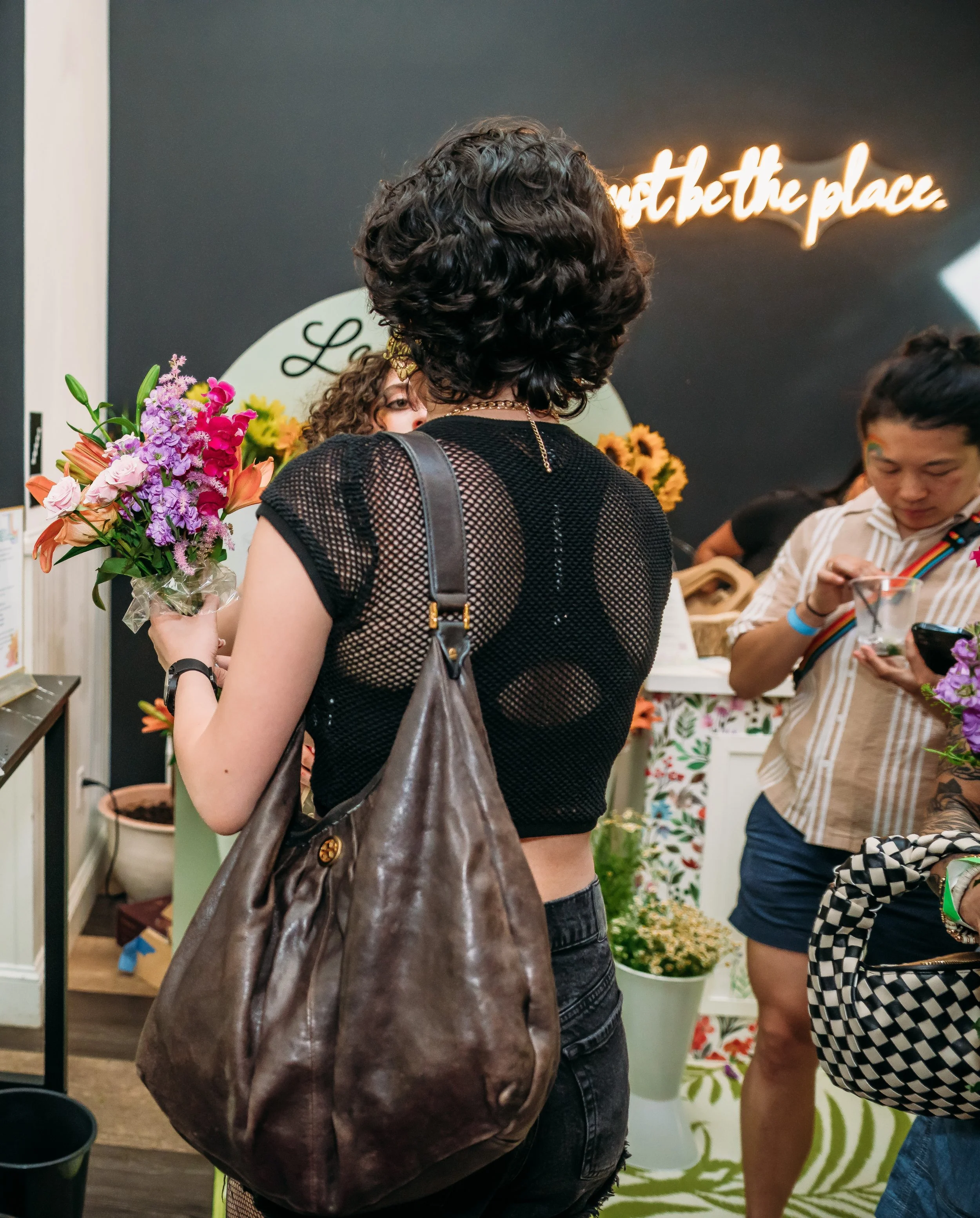 Bloom Bar setup at flower shop with woman holding bouquet of colorful flowers for wedding in Poconos, PA.
