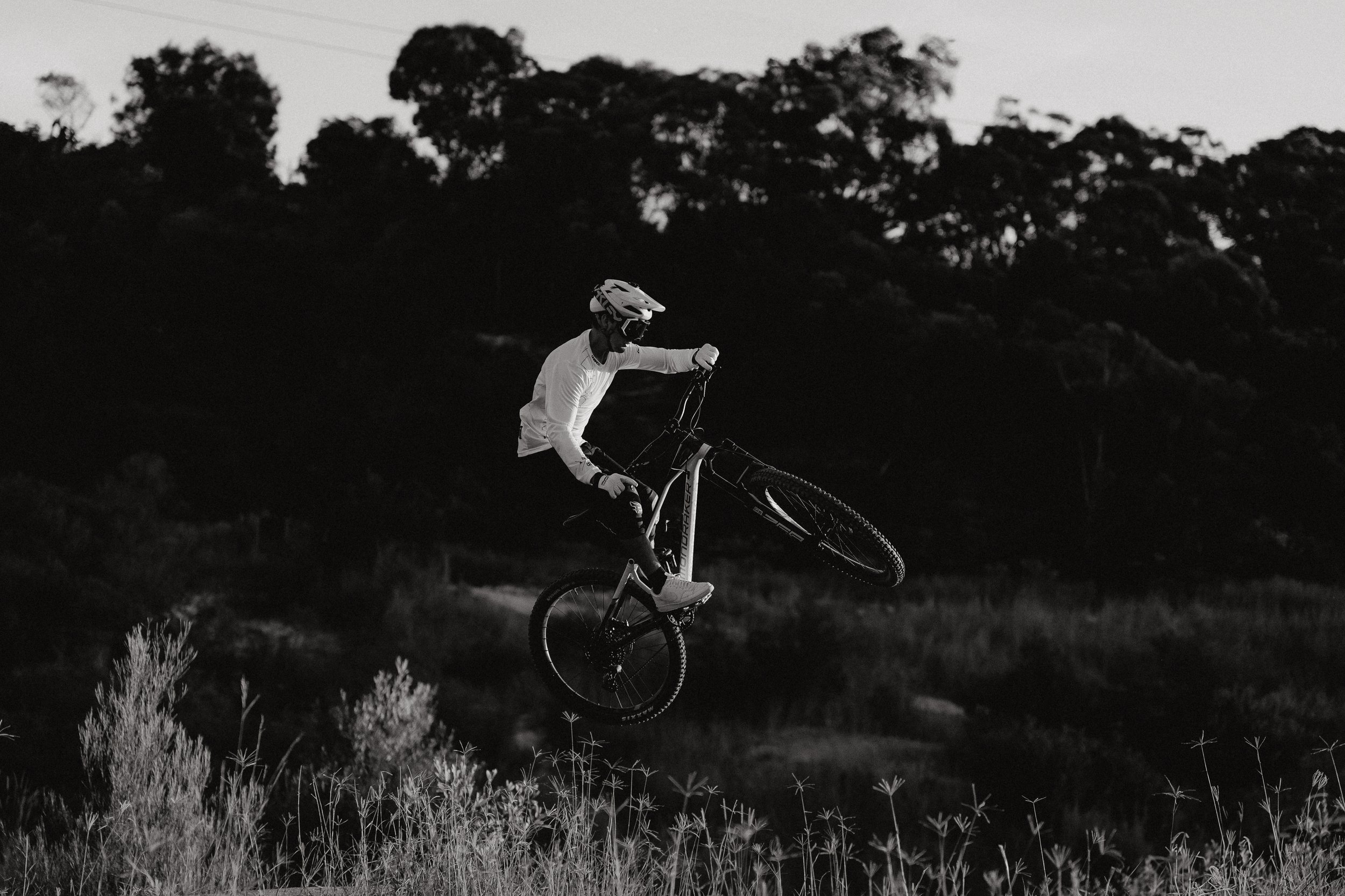 A person performing a jump on a mountain bike in a natural setting.