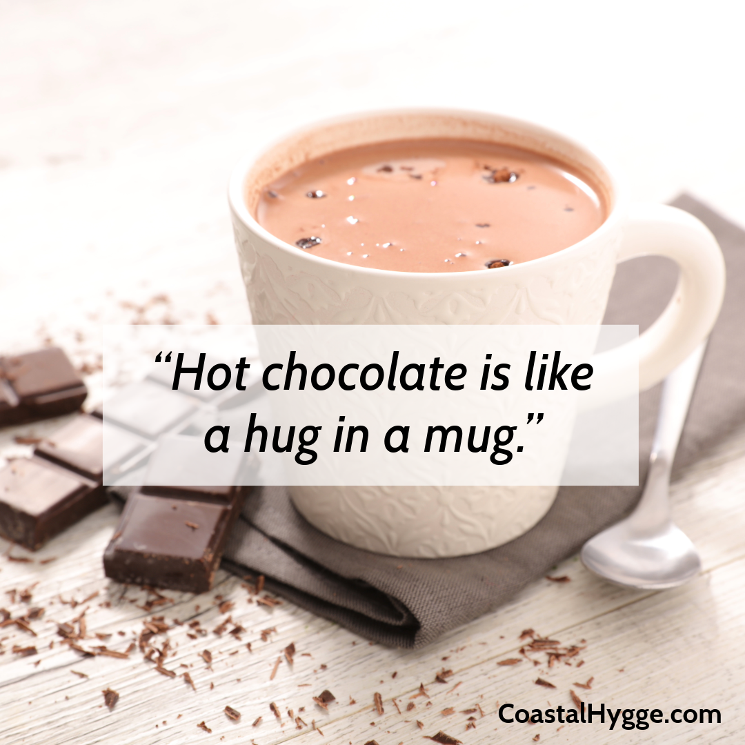 A cup of hot chocolate sitting on the brown-gray linen napkin, with chocolate bars sitting next to the cup. The quote said "Hot Chocolate is like a hug in a mug."